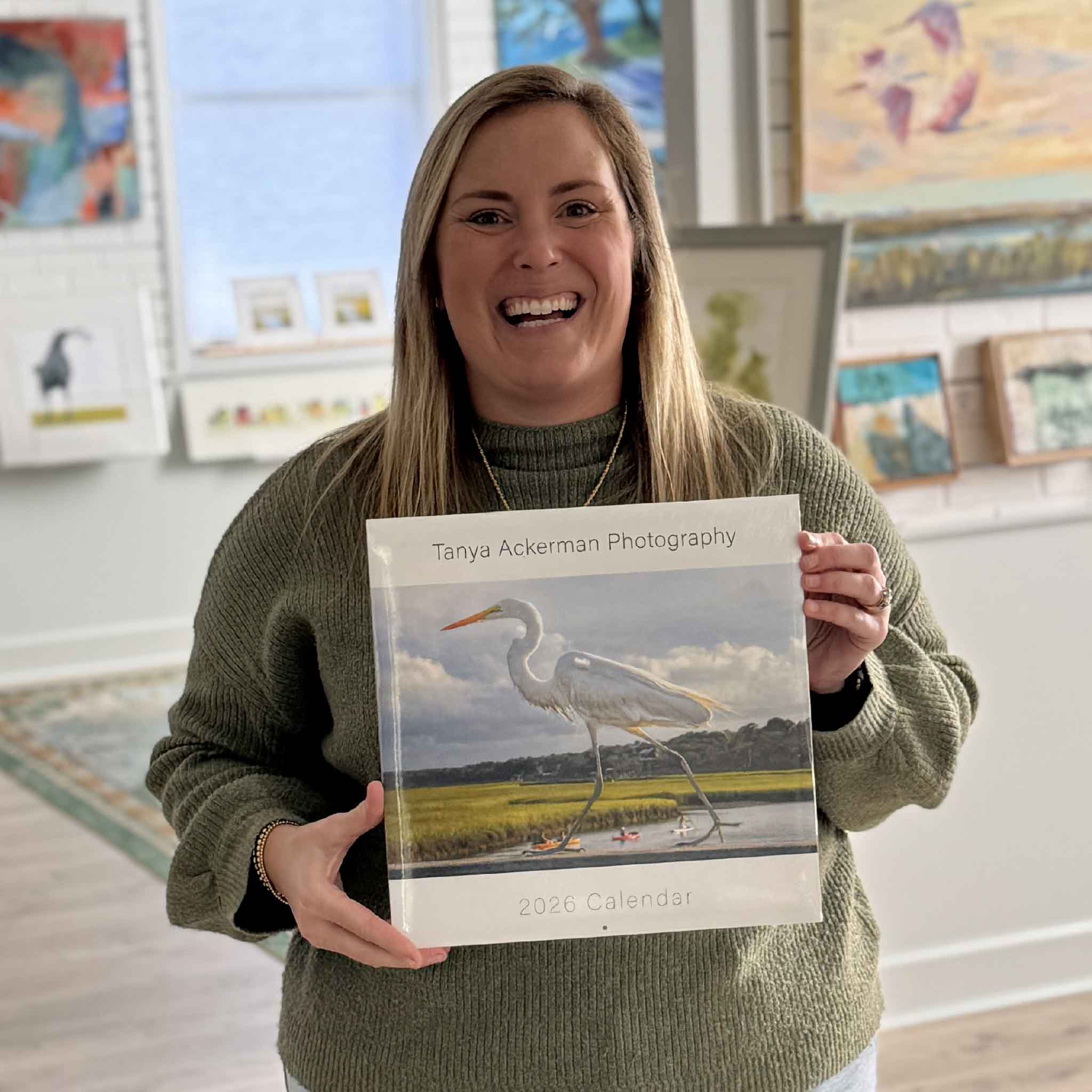 Team member holding the 2026 Pawleys Island photography calendar by local artist Tanya Ackerman inside Gray Man Gallery.
