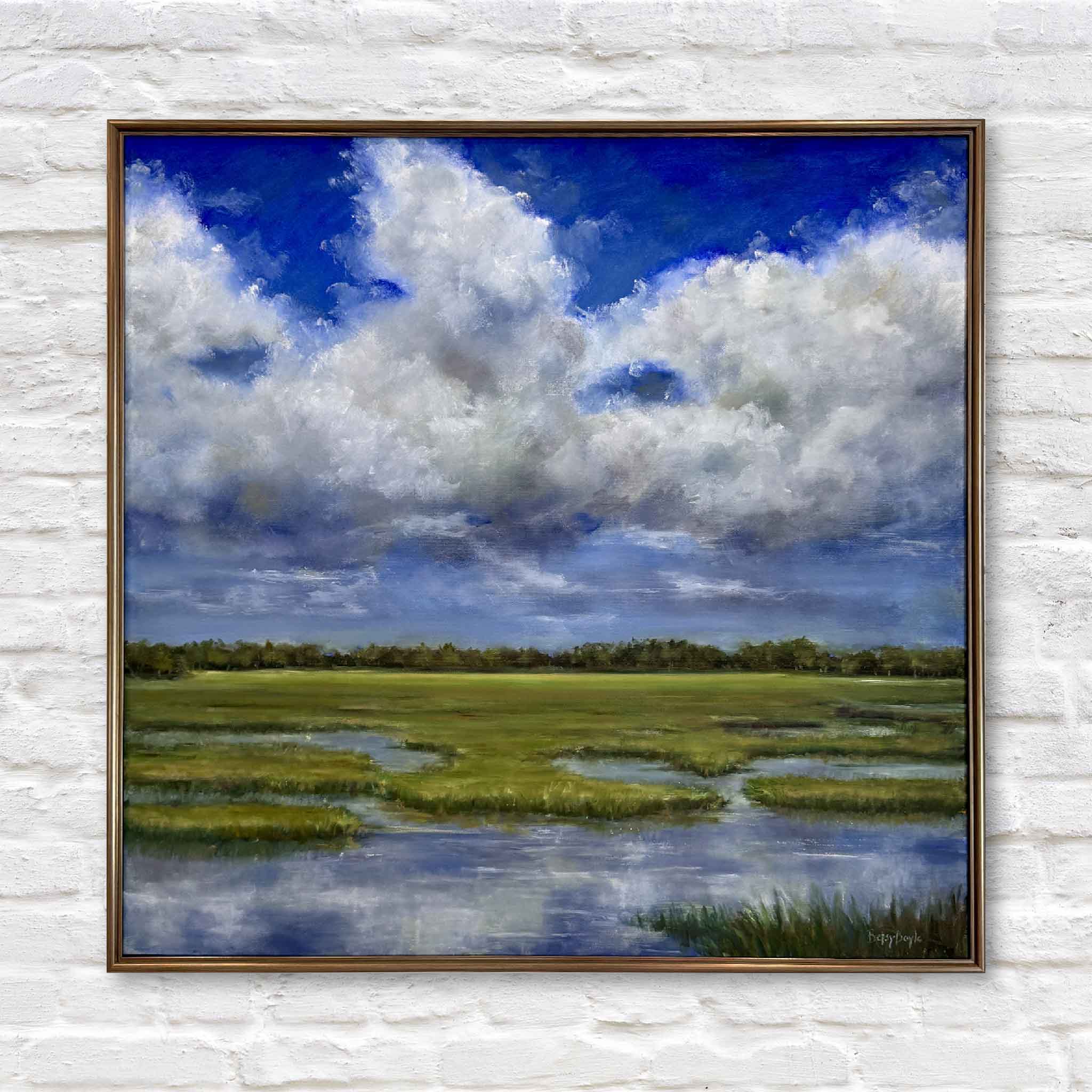 Framed oil painting of a serene Lowcountry marsh landscape under a dramatic sky filled with billowing white clouds. The scene features lush green grasses, reflective tidal pools, and a distant tree line, all set against a vibrant blue sky.