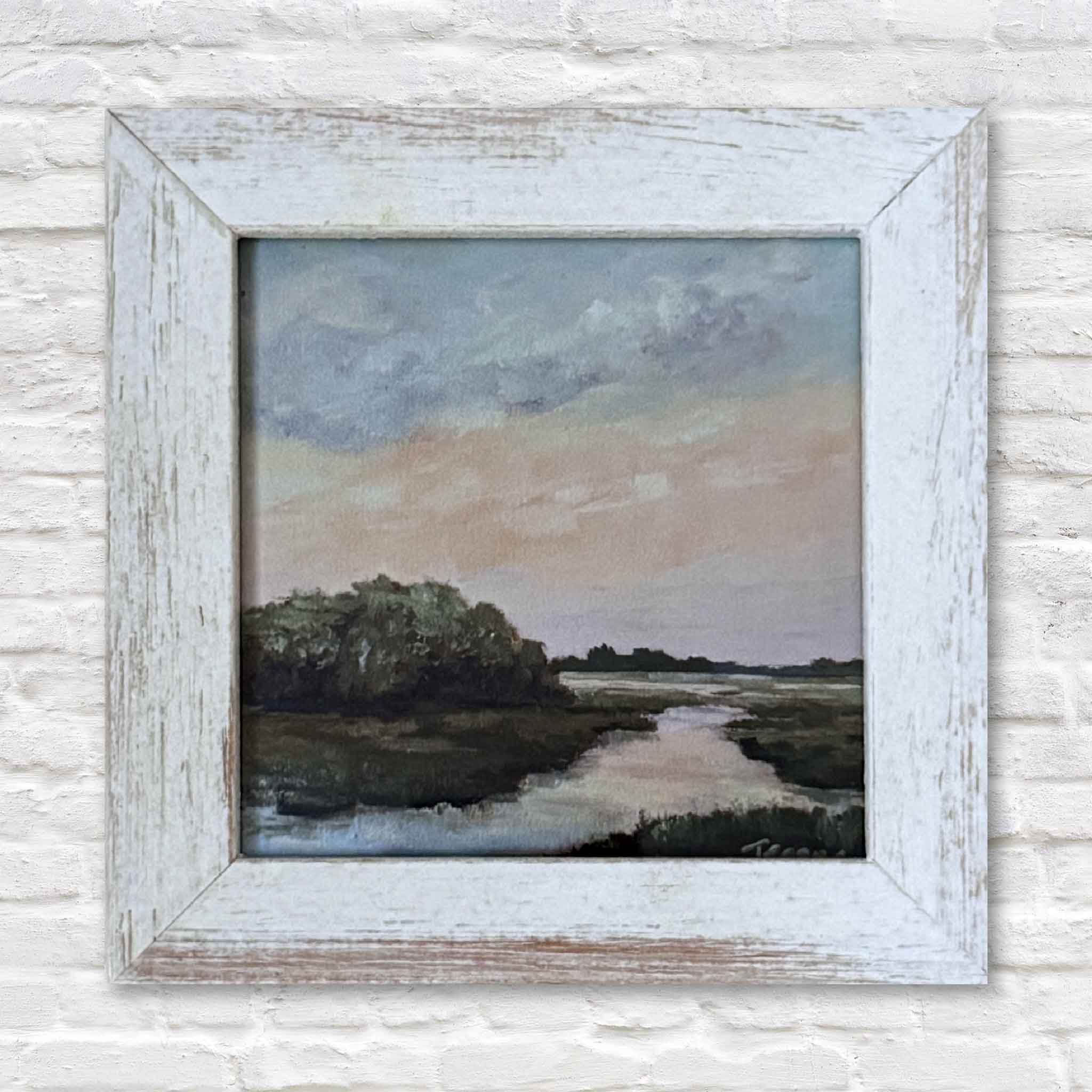 Framed painting of a landscape with a river and trees on a textured wall.