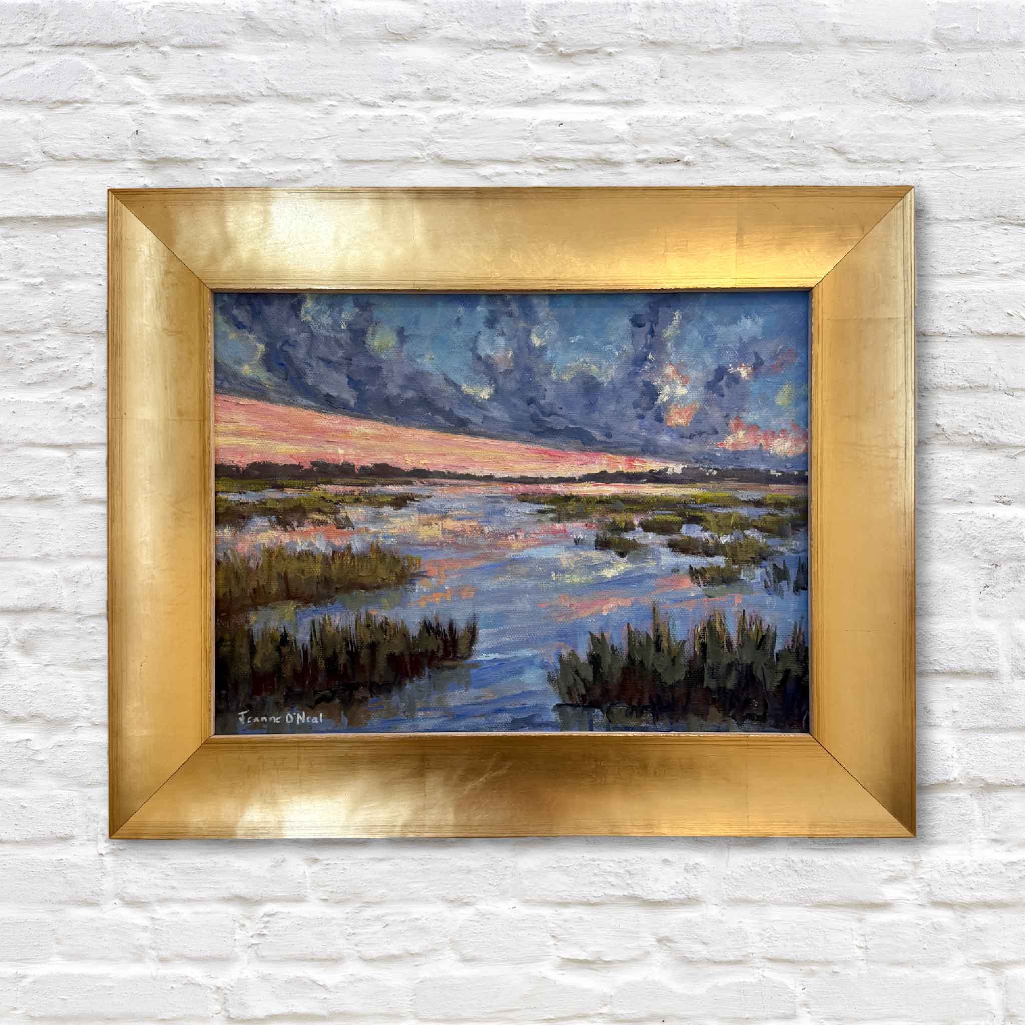 Framed painting of a landscape low country marsh with water and sky on a white brick wall