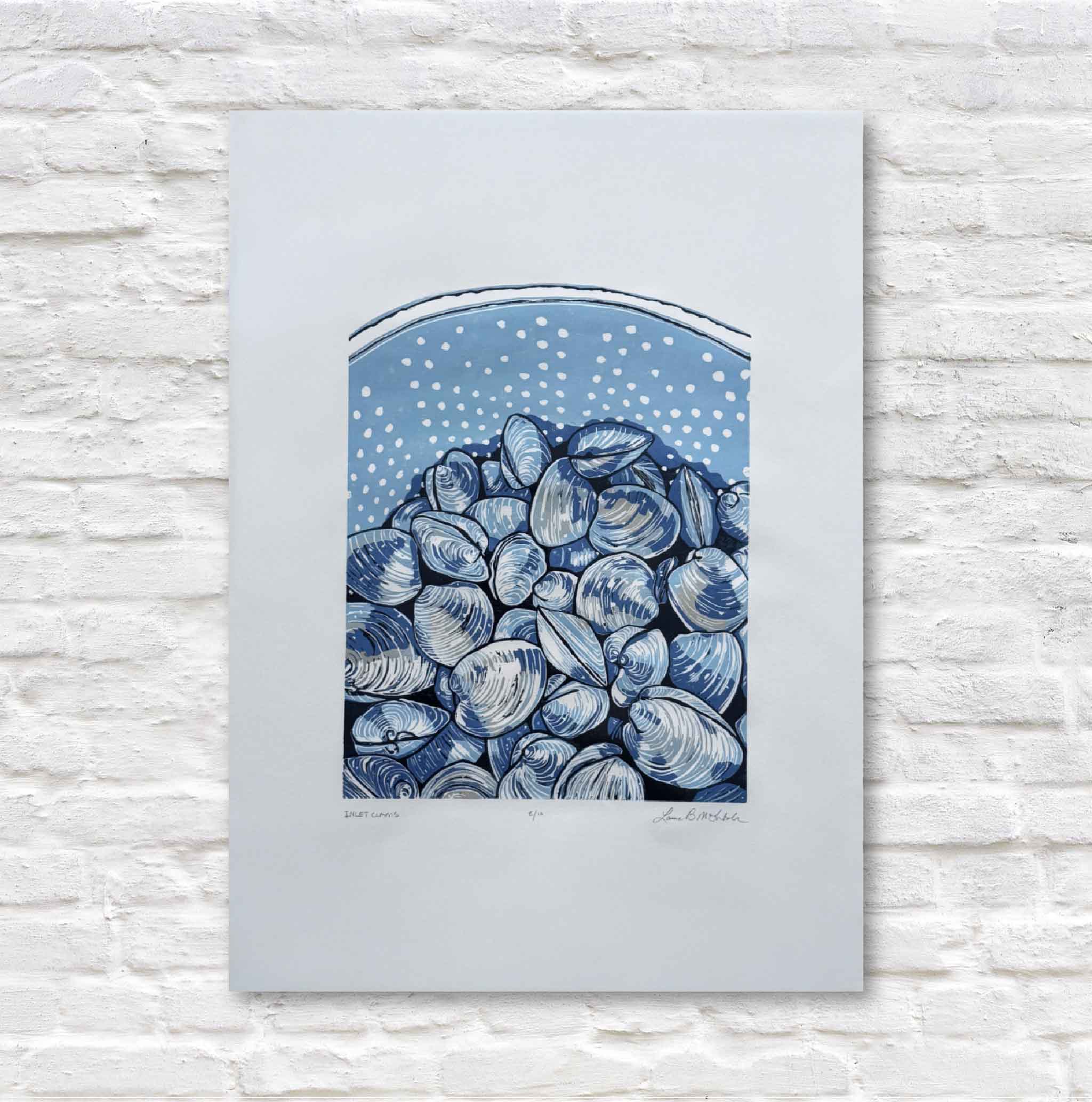 Art print of blue and white shells against a light blue background, framed on a textured white wall.