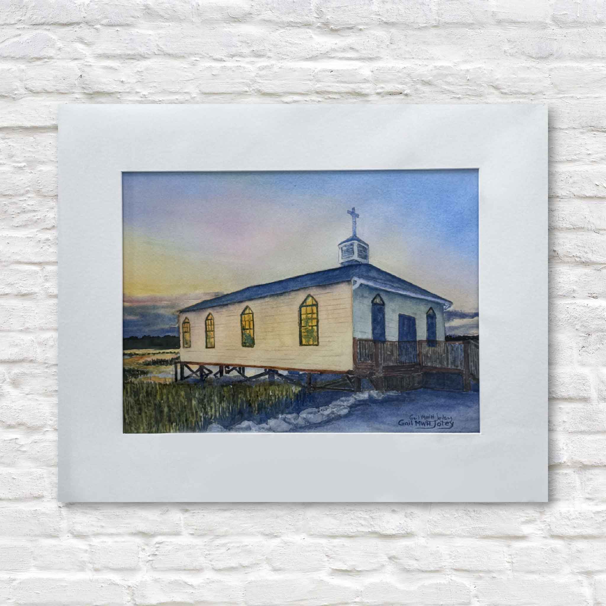 matted watercolor painting of the Pawleys Island chapel with a rainbow in the background on a textured white wall.