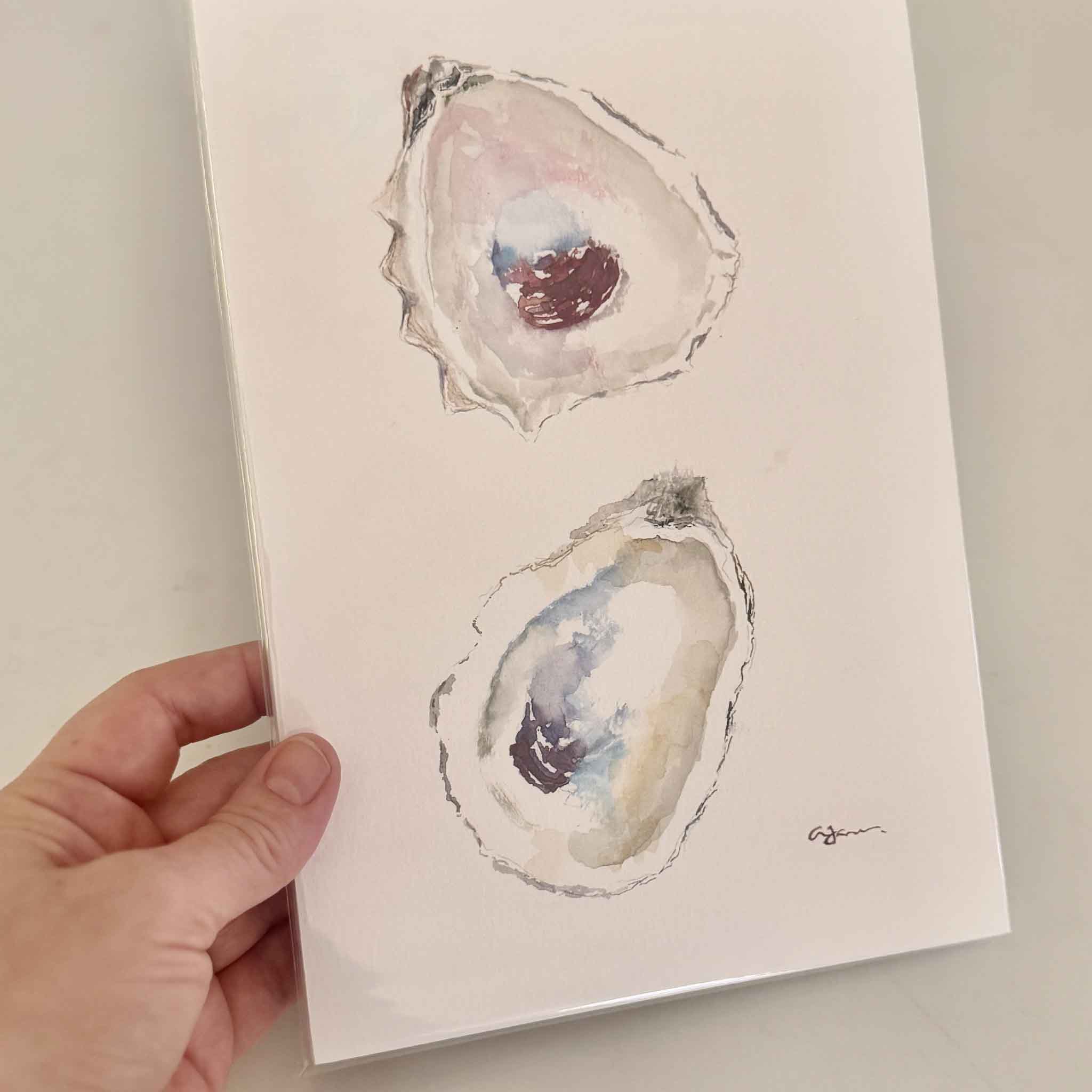 Signed, hand-painted watercolor of two oyster shells in blush, gray, and blue tones by Allison Farr, from her Lowcountry Jewels oyster collection.