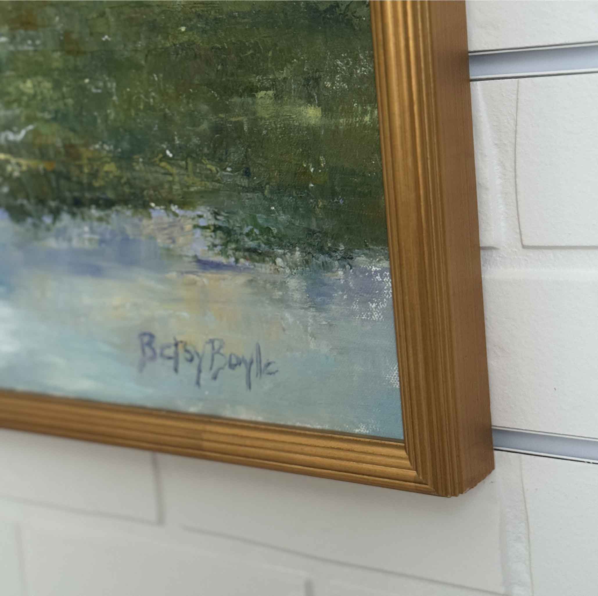 signature of artist Betsy Boyle on original artwork with a gold frame hanging on a white brick wall