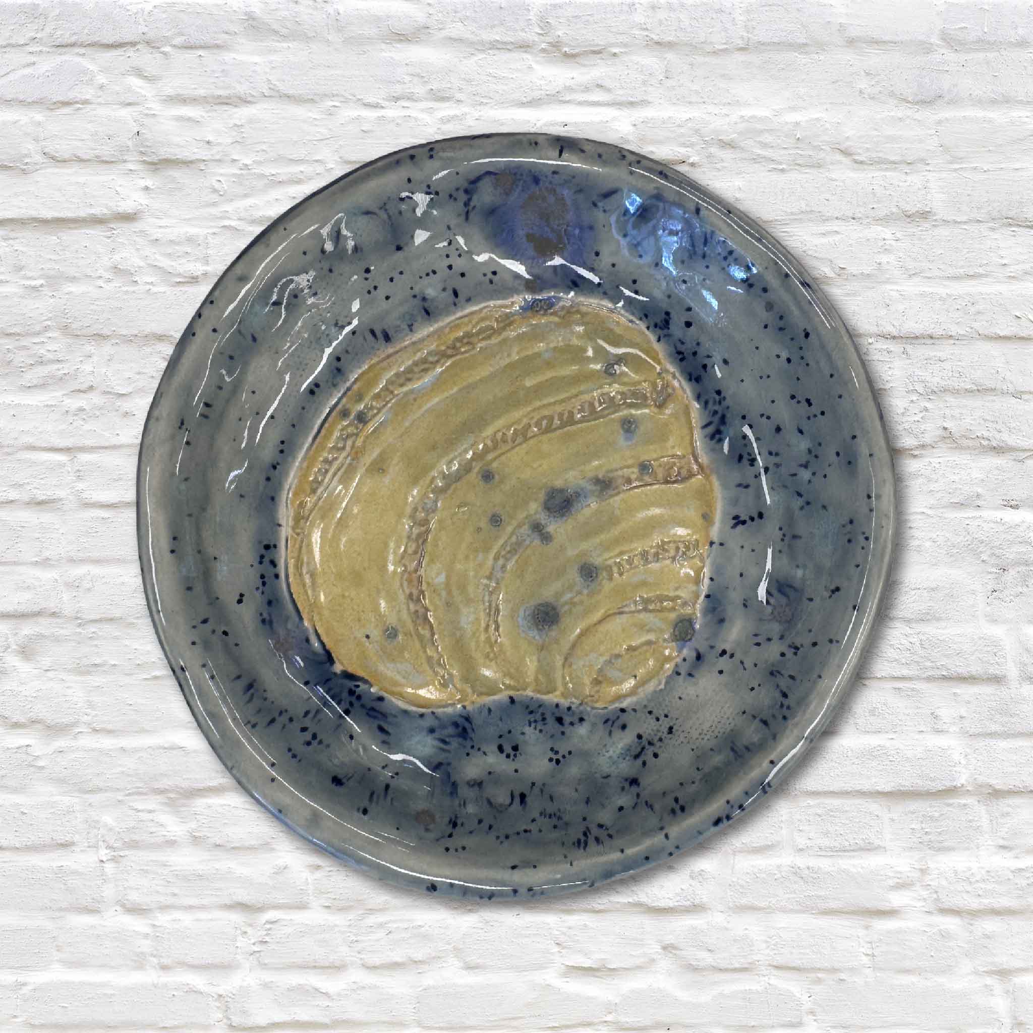 blue pottery dish with pawleys island shell design on white brick wall