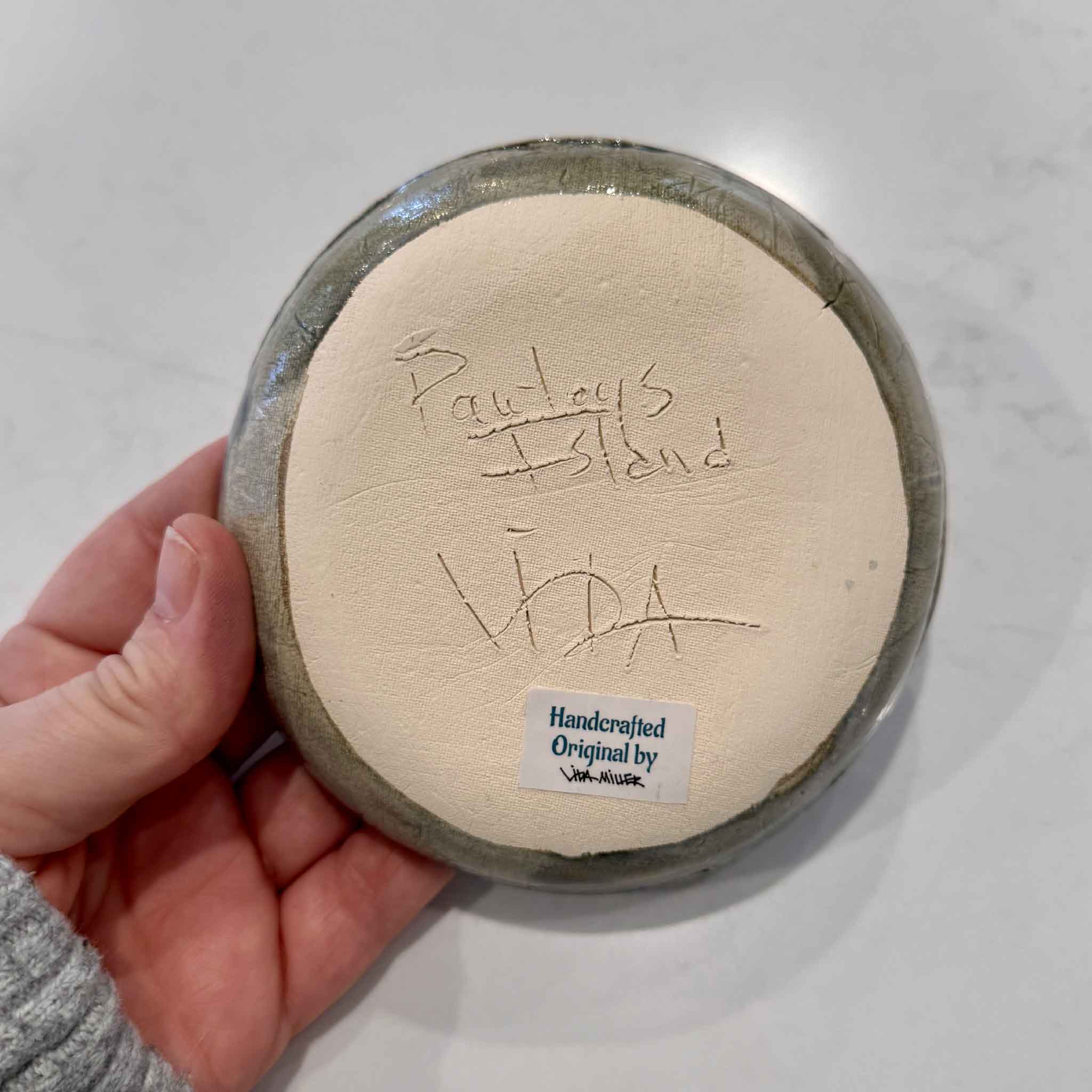 Handheld ceramic item with 'Vida' branding on a light background