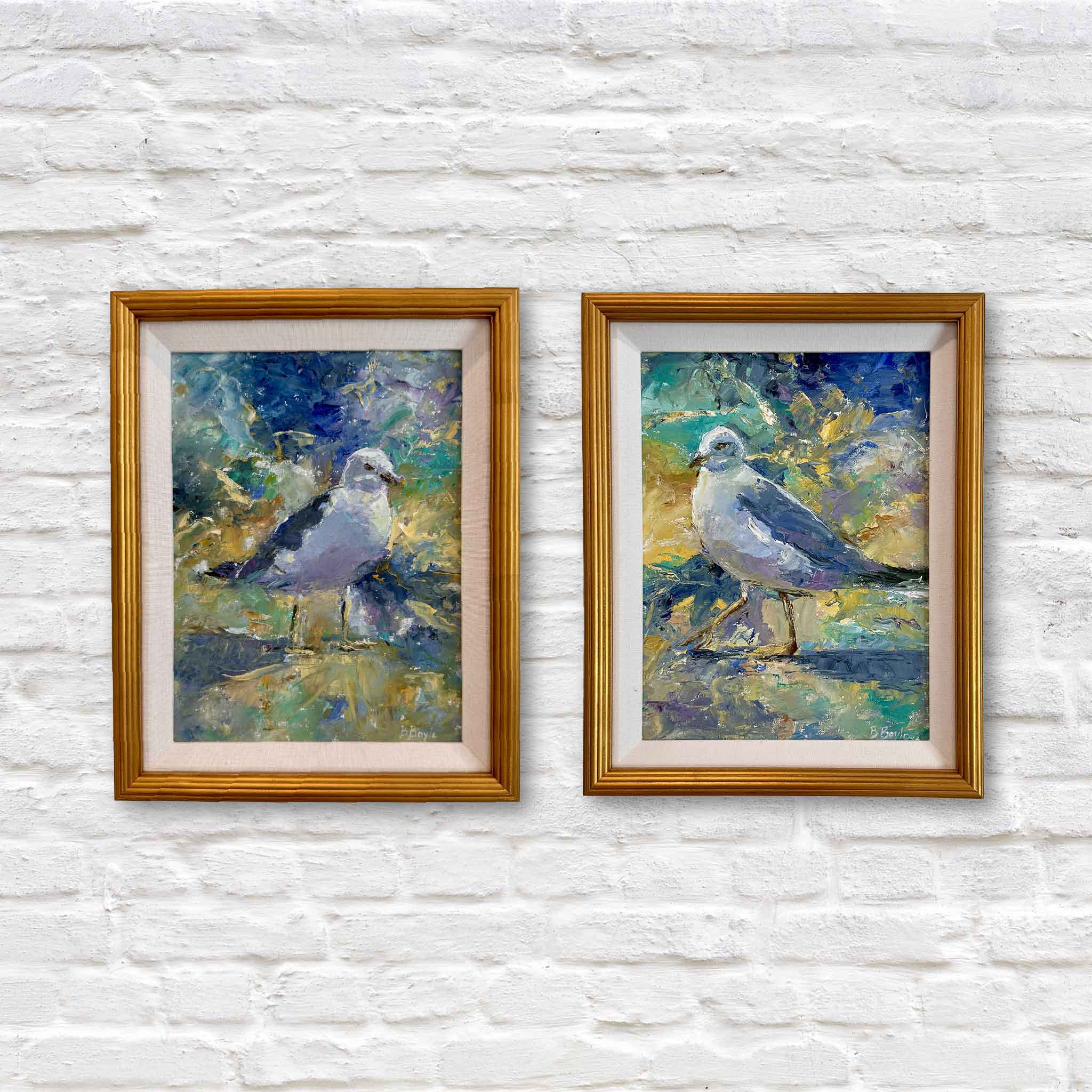 Two framed oil paintings of sea gulls with a colorful background on a white brick wall
