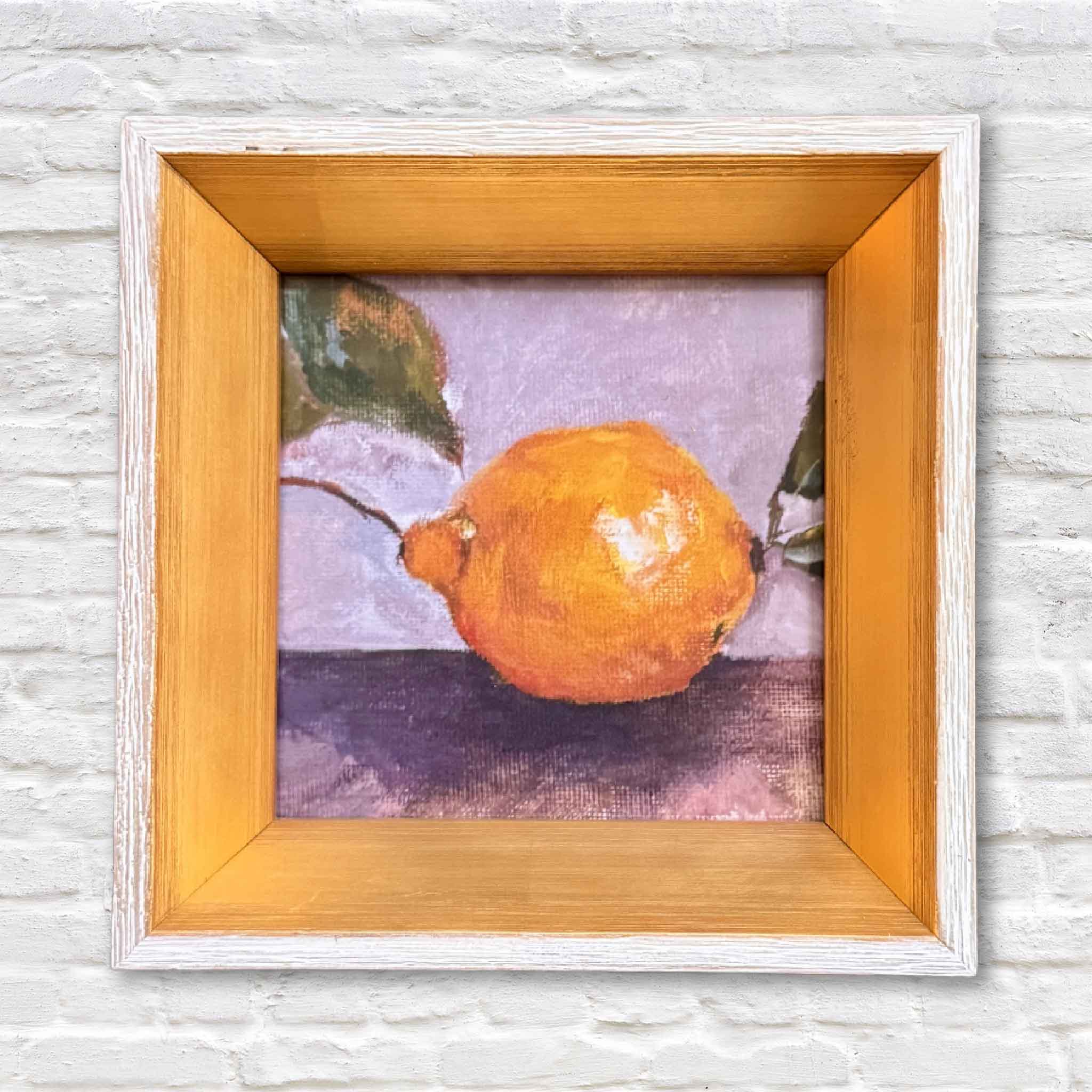 framed artwork of a lemon hanging on a white brick wall