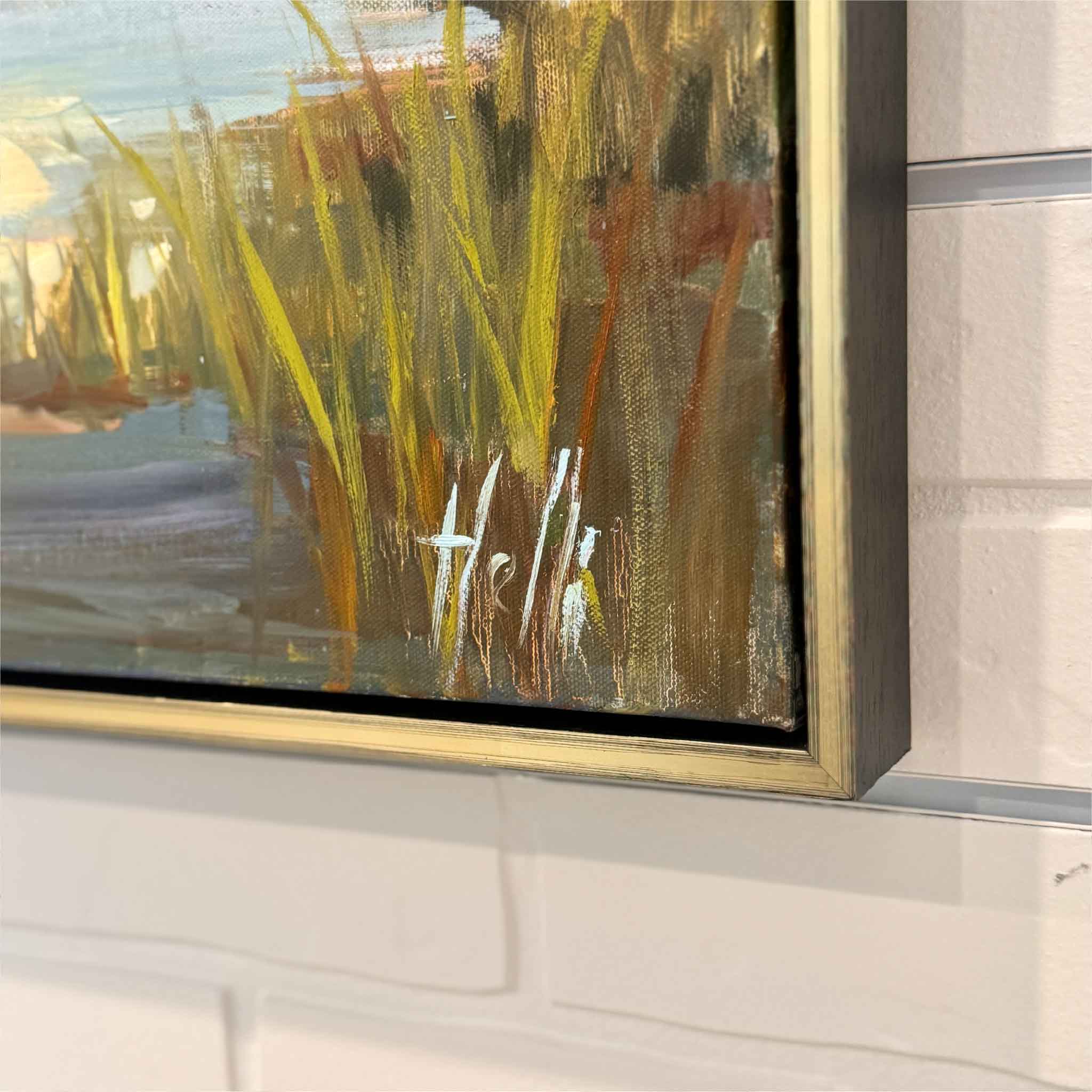 Artist signature on an framed original oil painting hanigng on a white brick wall
