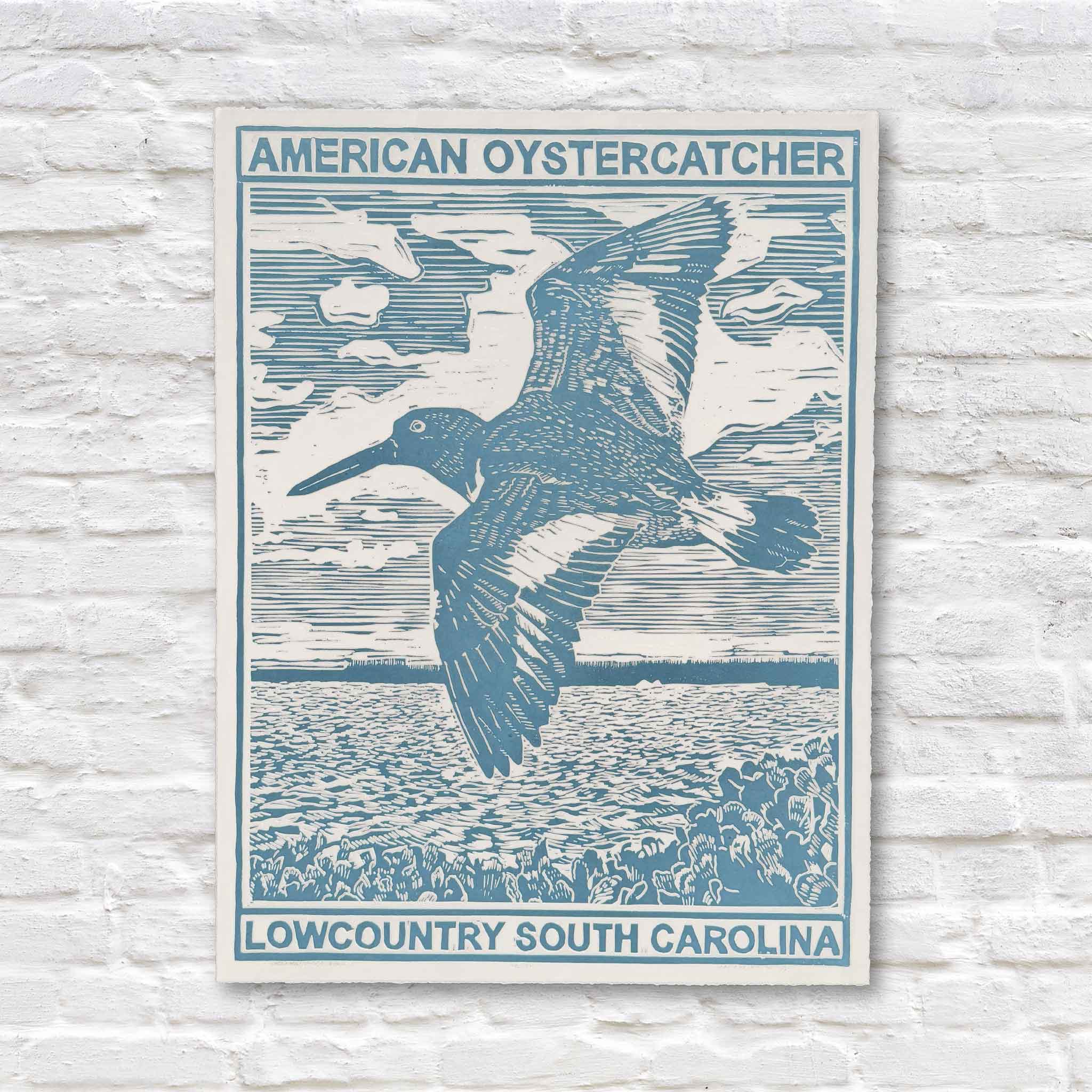 Blue linocut artwork of an oystercatcher bird flying over coastal marsh on a white brick background
