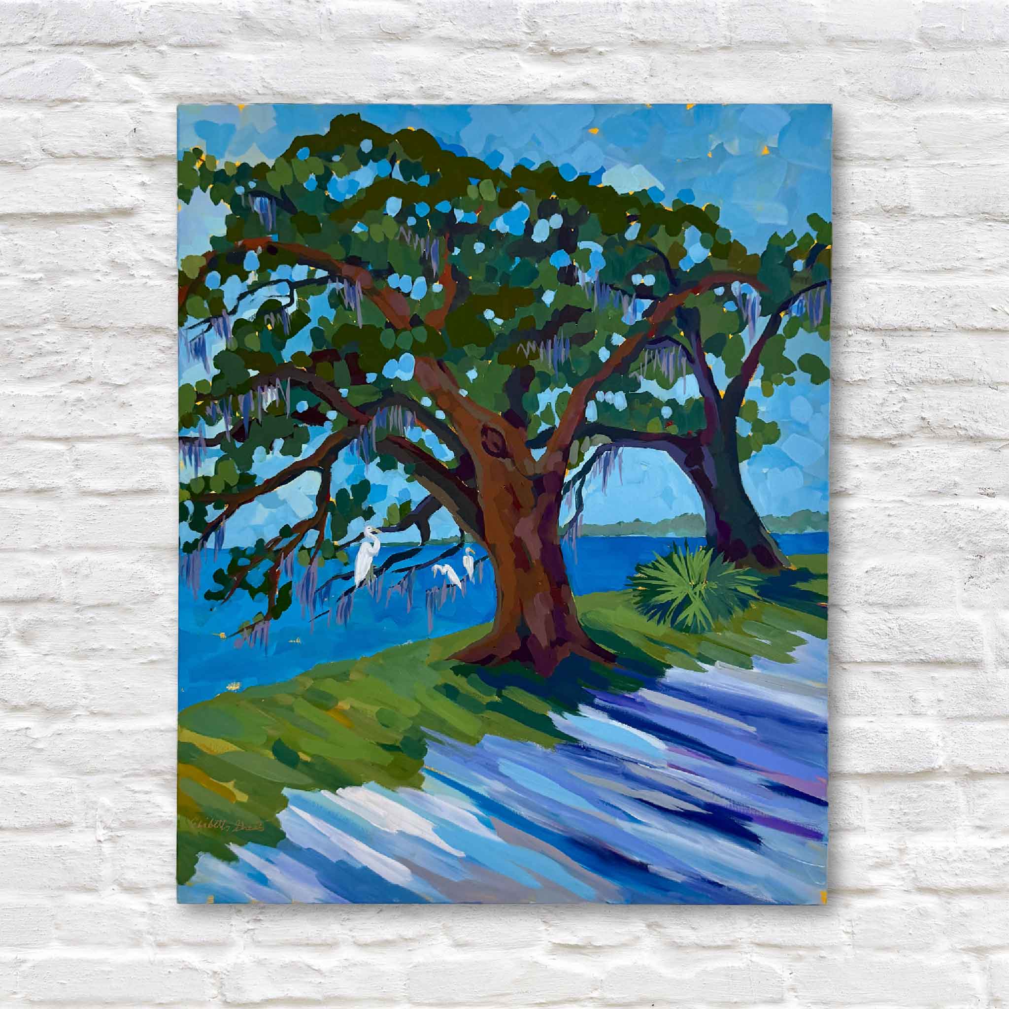 Colorful mixed media artwork of lowcountry trees and water against a white brick wall