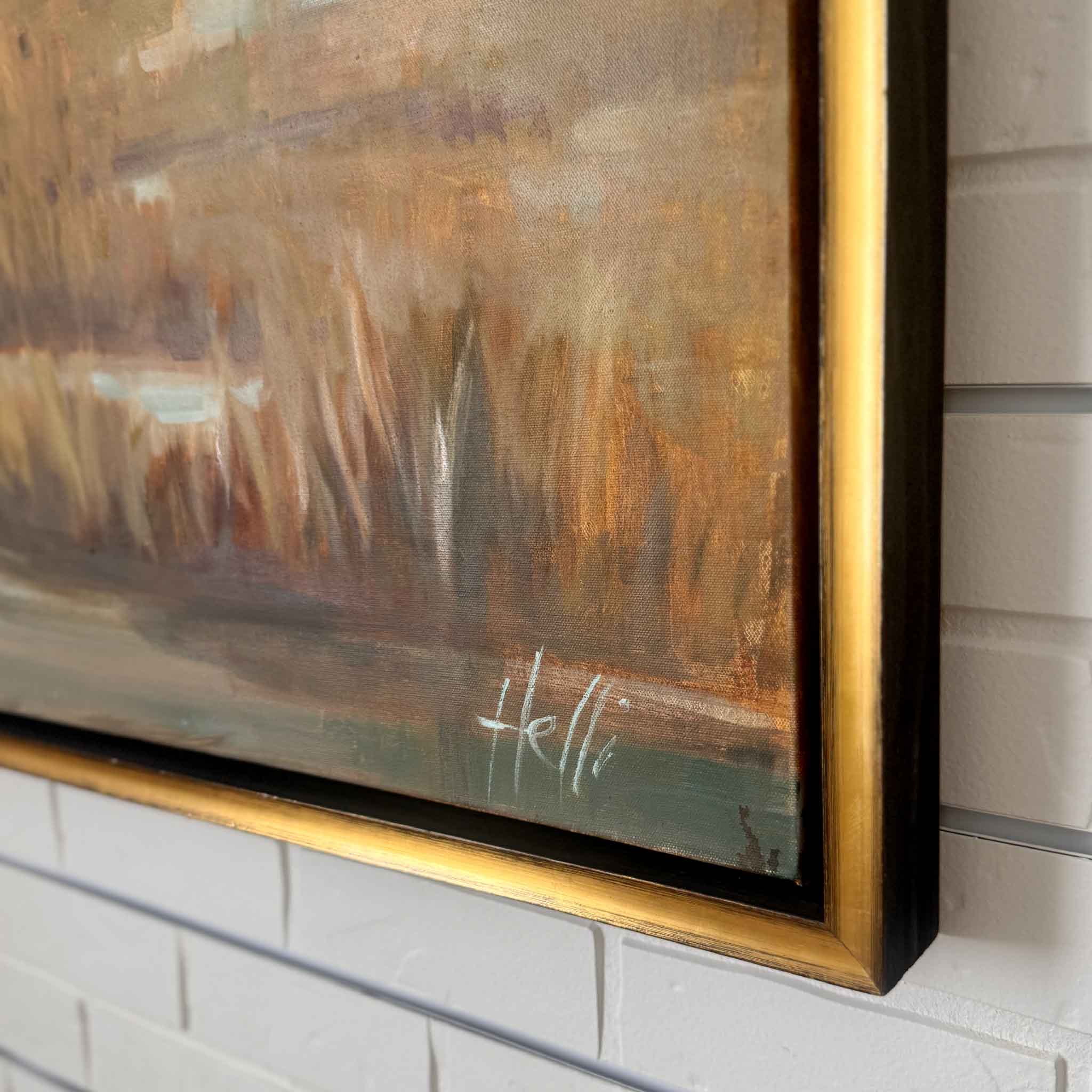 Abstract painting with a gold frame on a white brick wall