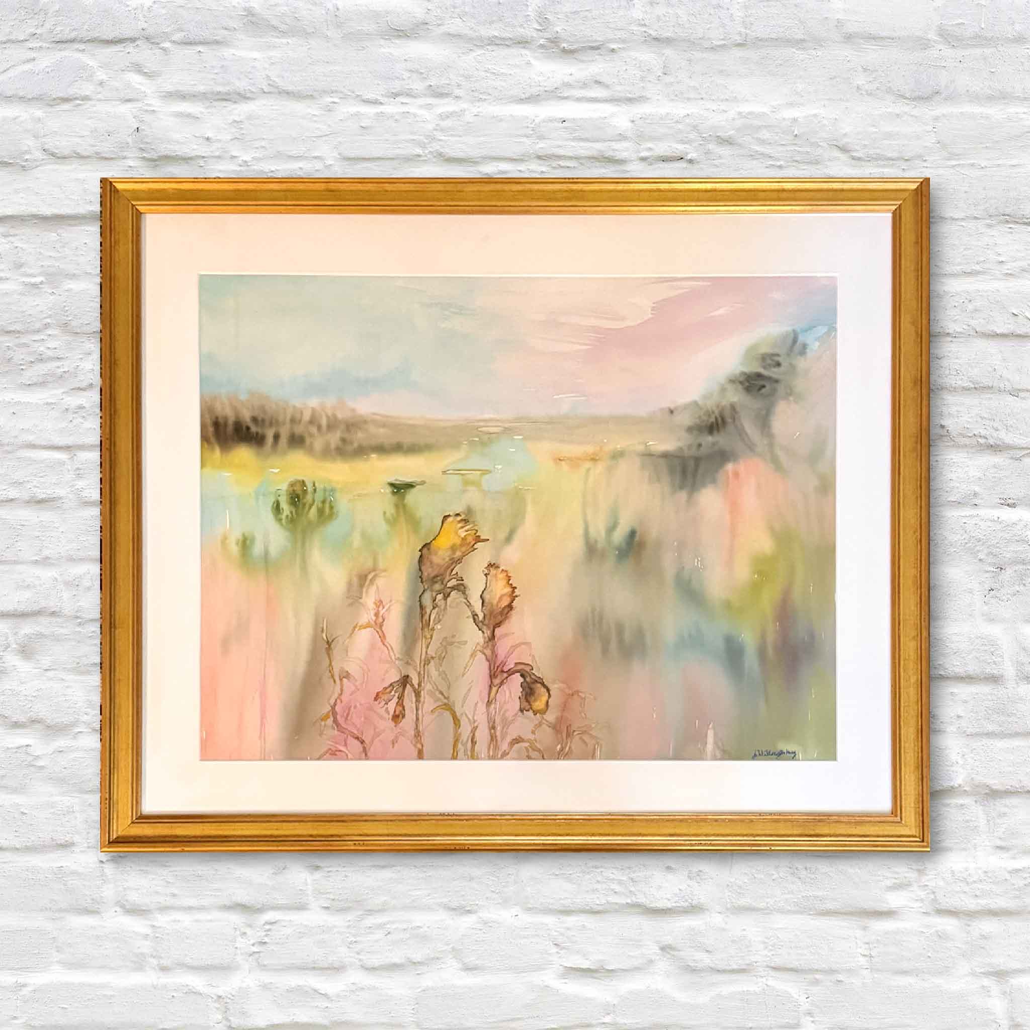 “Summer Haze” watercolor painting by Joanne Willoughby featuring a dreamy Lowcountry marsh scene with soft pastel colors, framed in gold and displayed at Gray Man Gallery in Pawleys Island, SC.