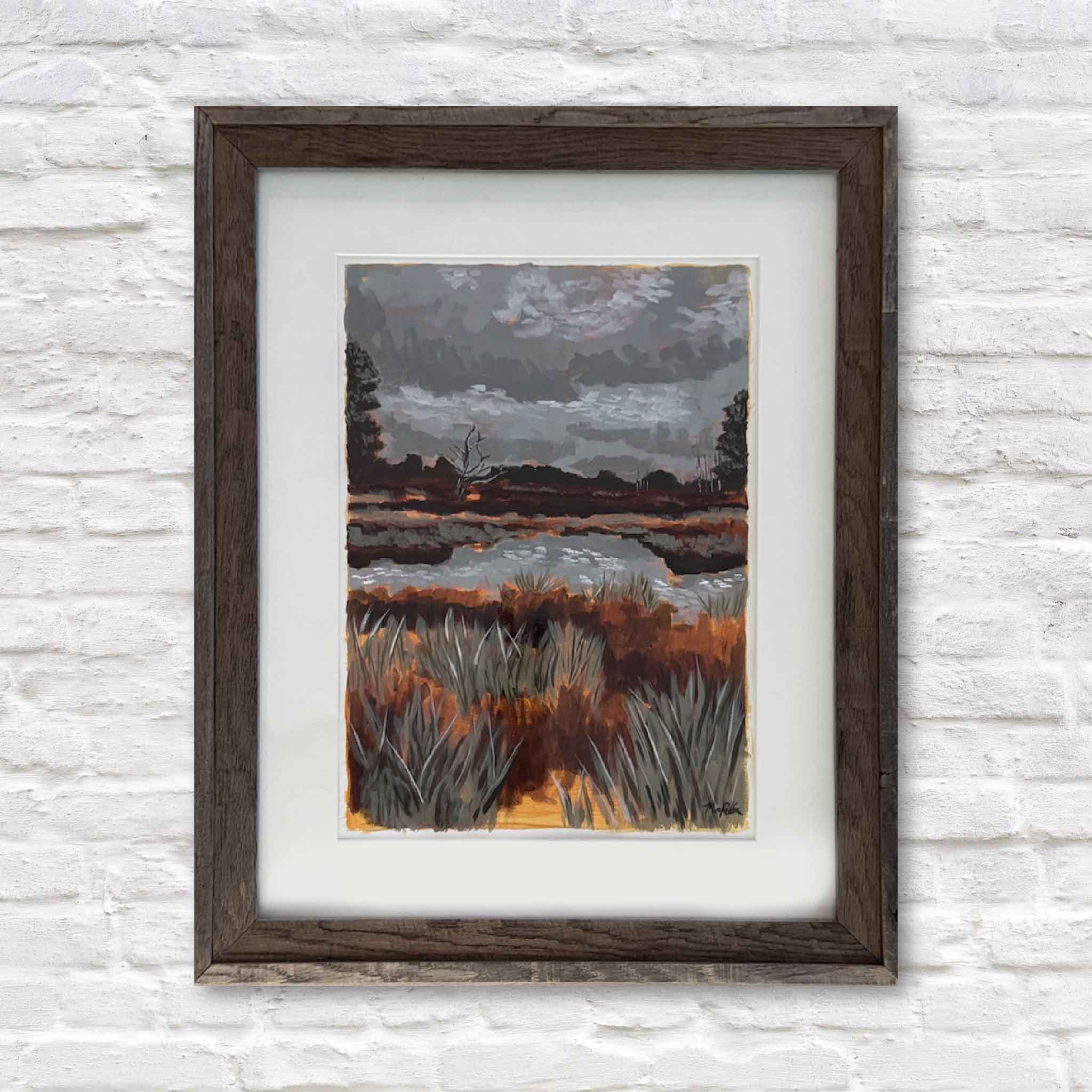 Framed artwork of a landscape with trees and water on a textured white wall.