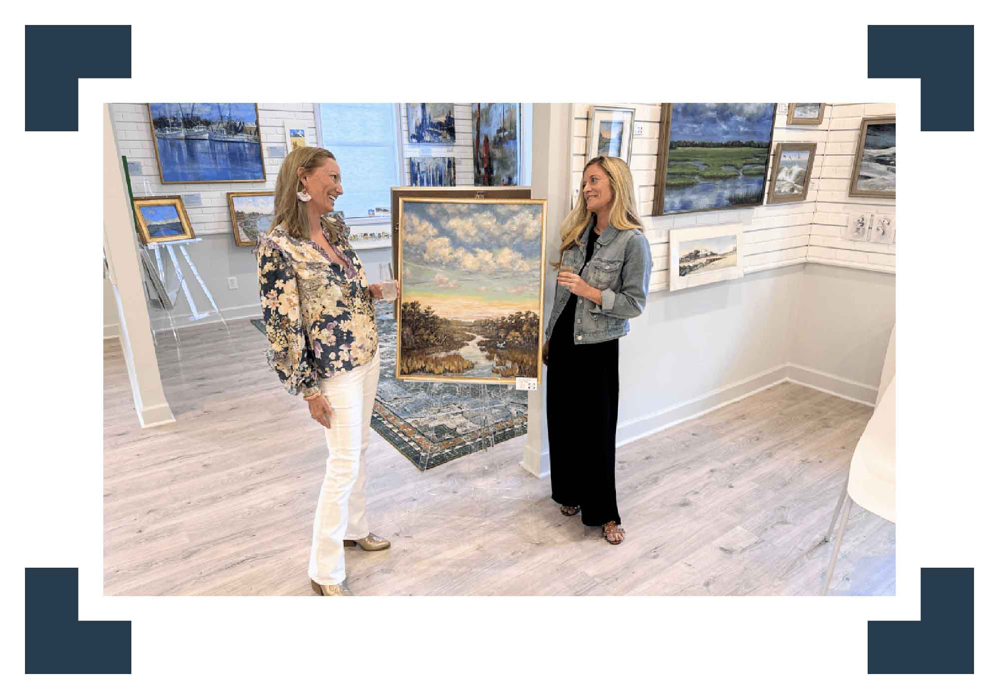 Two women in an art gallery discussing a painting.
