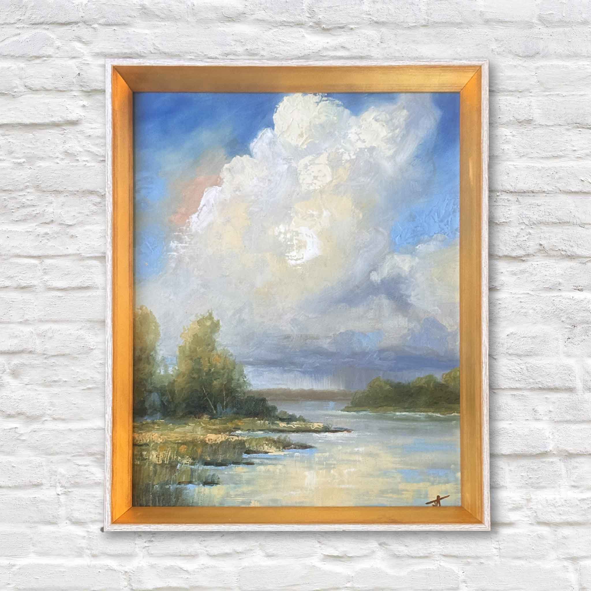 Framed oil painting Clearing Skies by meteorologist Jamie Arnold, featuring sunlight over a Lowcountry marsh with rain clouds in the distance.