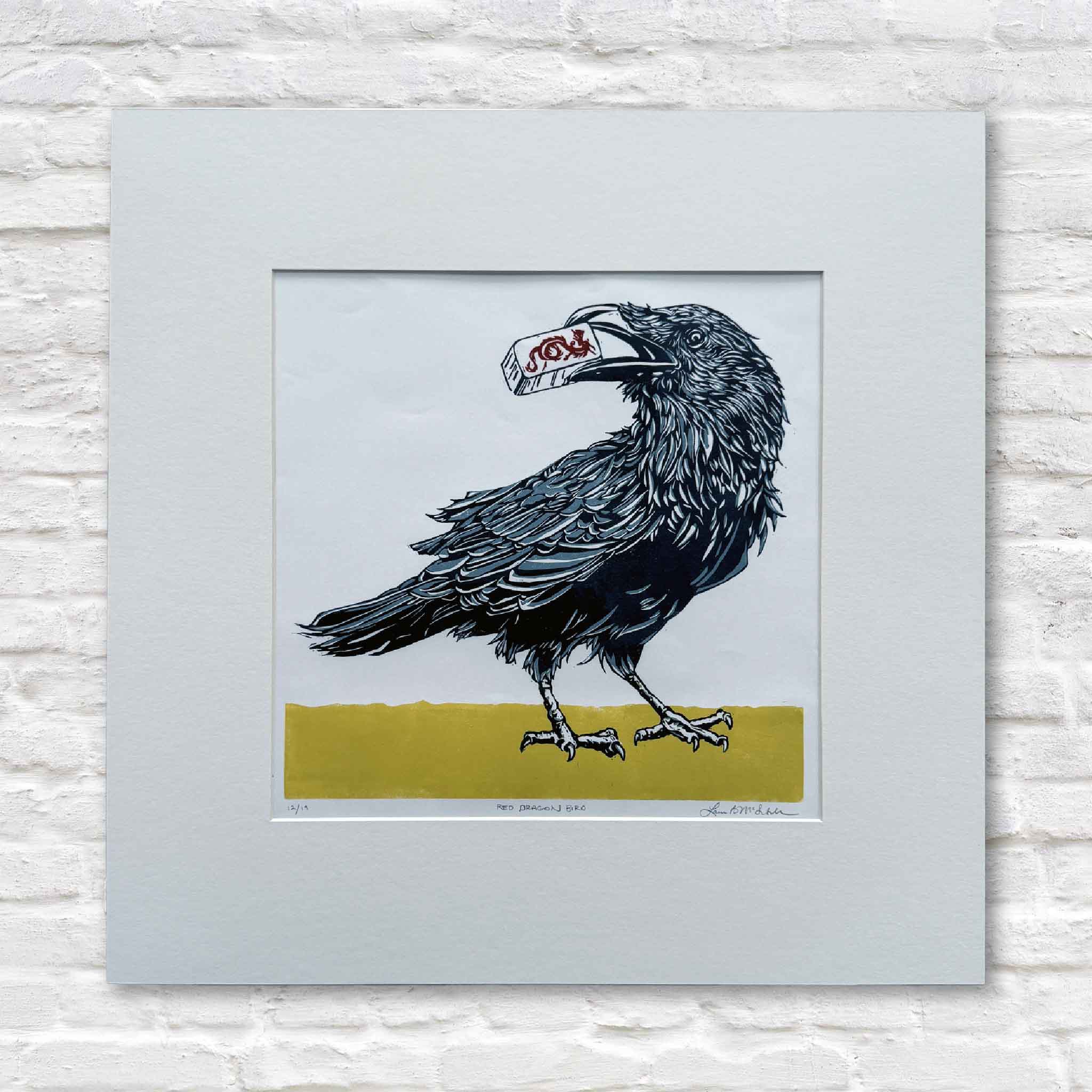 Original linocut by Laurie McIntosh of a blackbird holding a Red Dragon mahjong tile, signed and numbered, matted to 20×20 inches