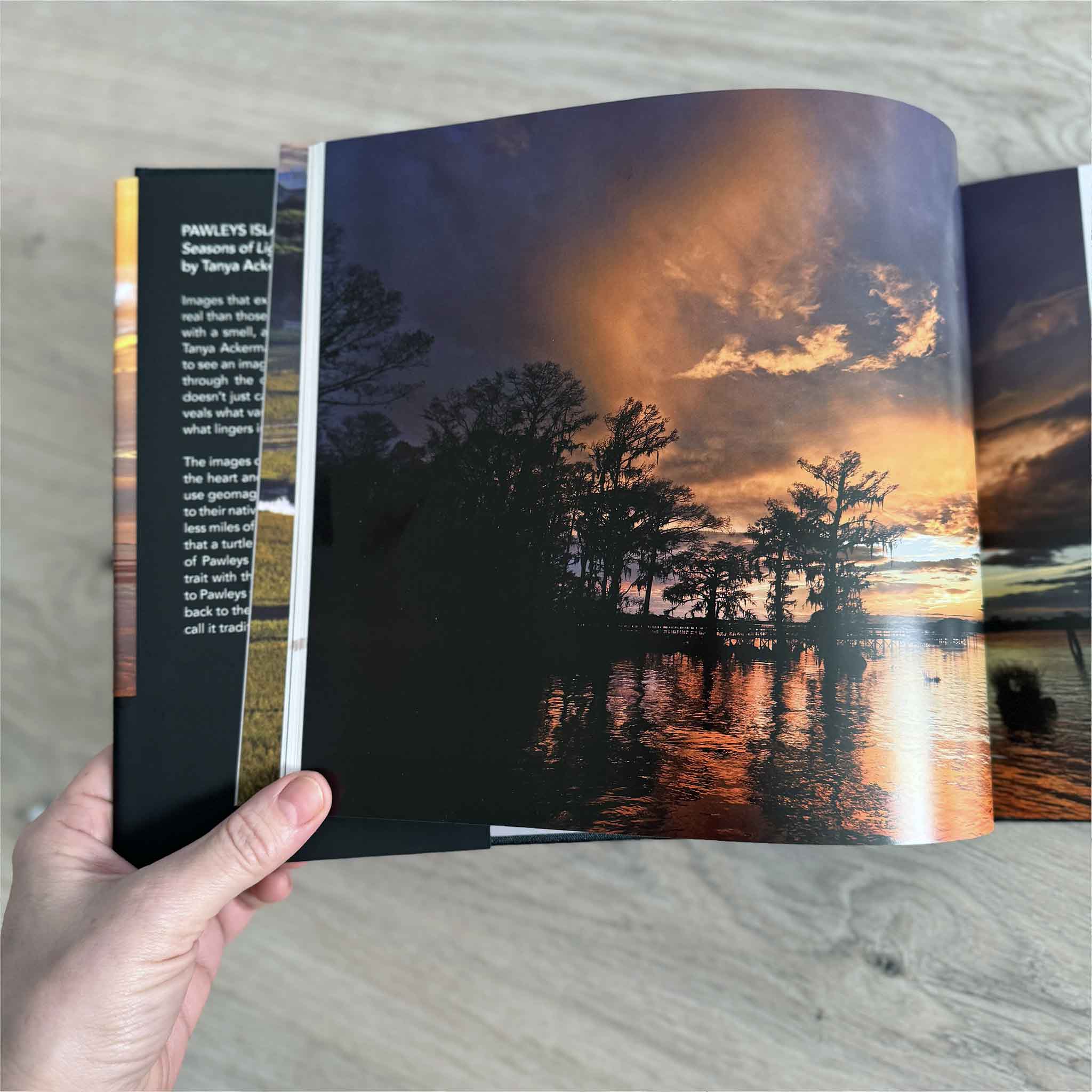 Front cover of Pawleys Island: Seasons of Light by Tanya Ackerman, Beach Cover Edition, showing a vivid sunset over Pawleys Island with homes and shoreline reflected in the water.