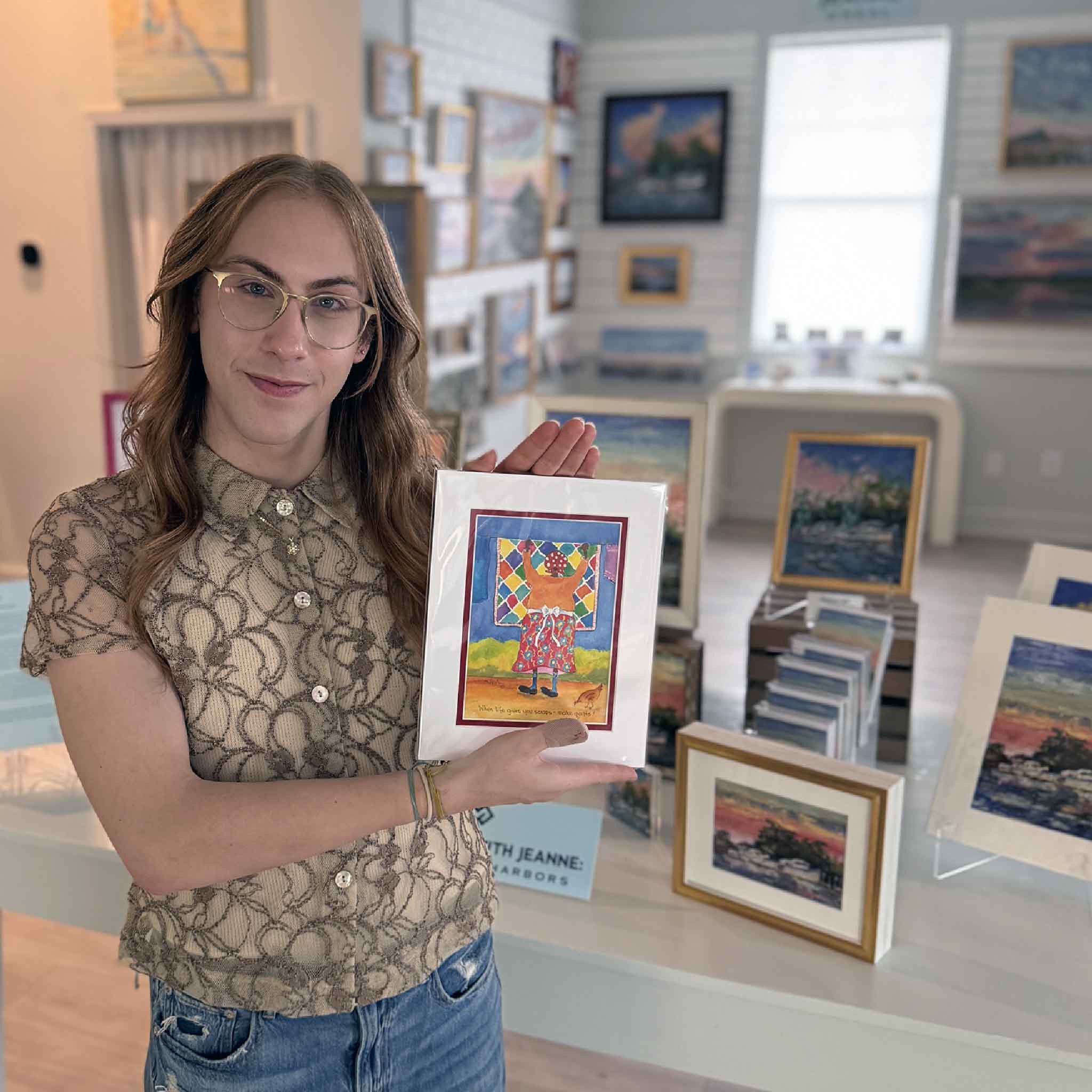 Matted 8x10 print of Vida Miller’s “When Life Gives You Scraps, Make Quilts” featuring a woman hanging a colorful quilt on a clothesline. Pictured at Gray Man Gallery in Pawleys Island.