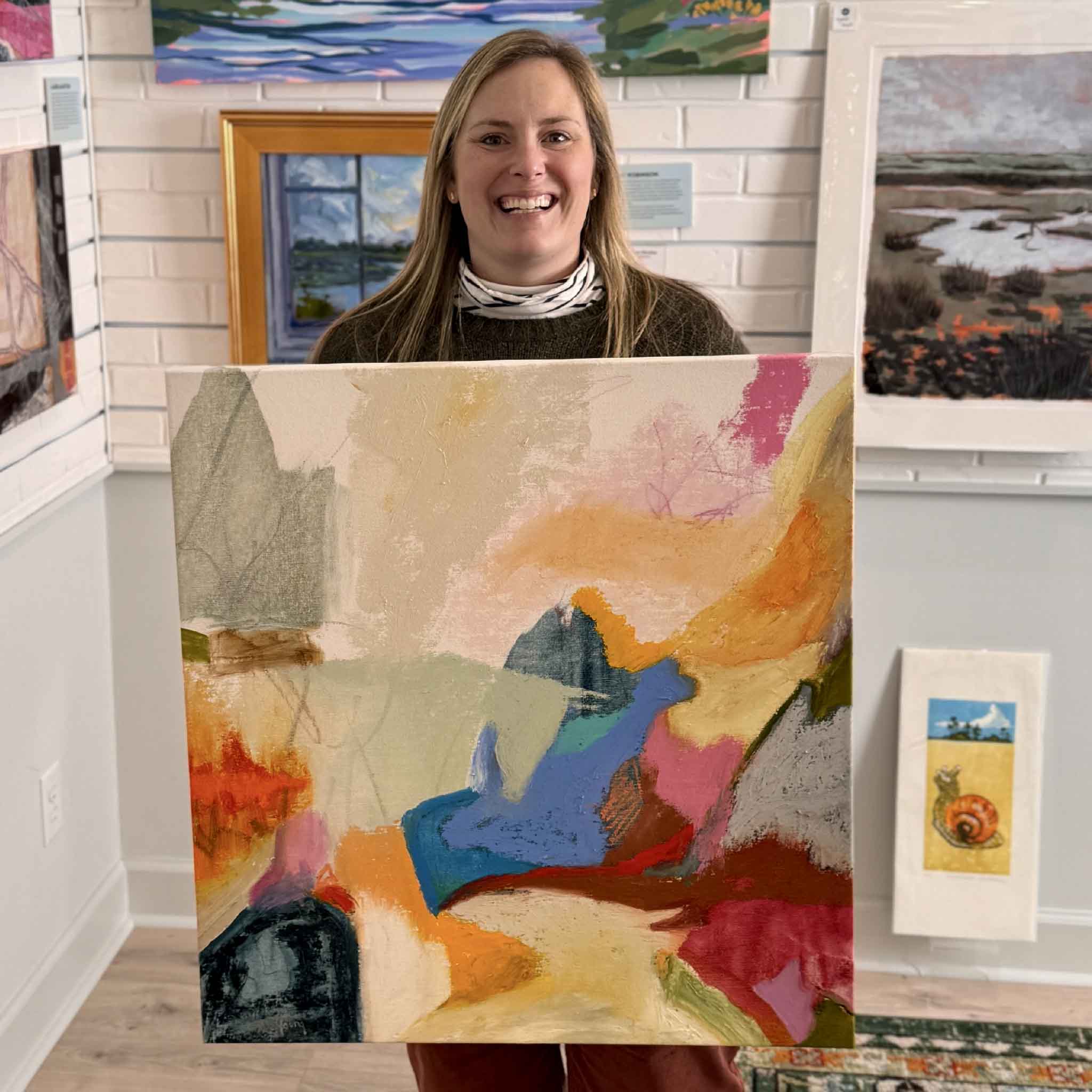 Bordy holding “Abstract #10,” an original mixed media painting by Caroline Young, inside Gray Man Gallery in Pawleys Island, showing scale, texture, and vibrant coastal-inspired color palette