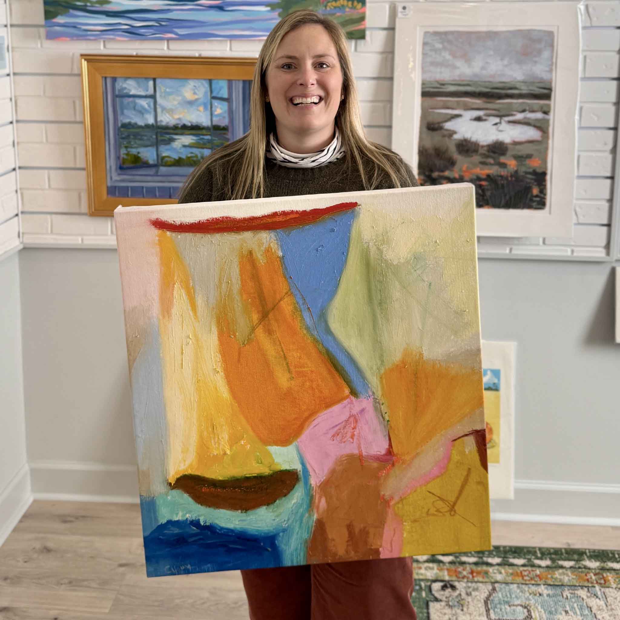 Gray Man Gallery team member Bordy holding Abstract No. 8 by local artist Caroline Young inside the Pawleys Island gallery, showing scale and detail of the colorful mixed media abstract painting in a coastal South Carolina art space
