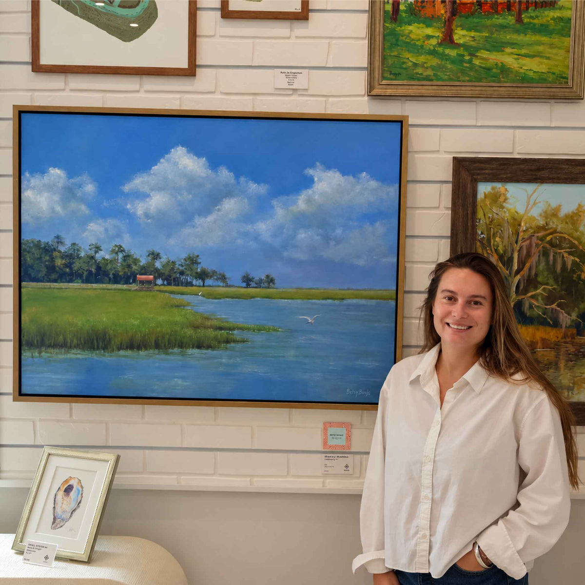 Blue and Green of Summer II by local South Carolina artist Betsy Boyle displayed at Gray Man Gallery in Pawleys Island, an original framed oil painting featuring vivid green coastal marsh, blue tidal water, soaring egret and dramatic summer clouds