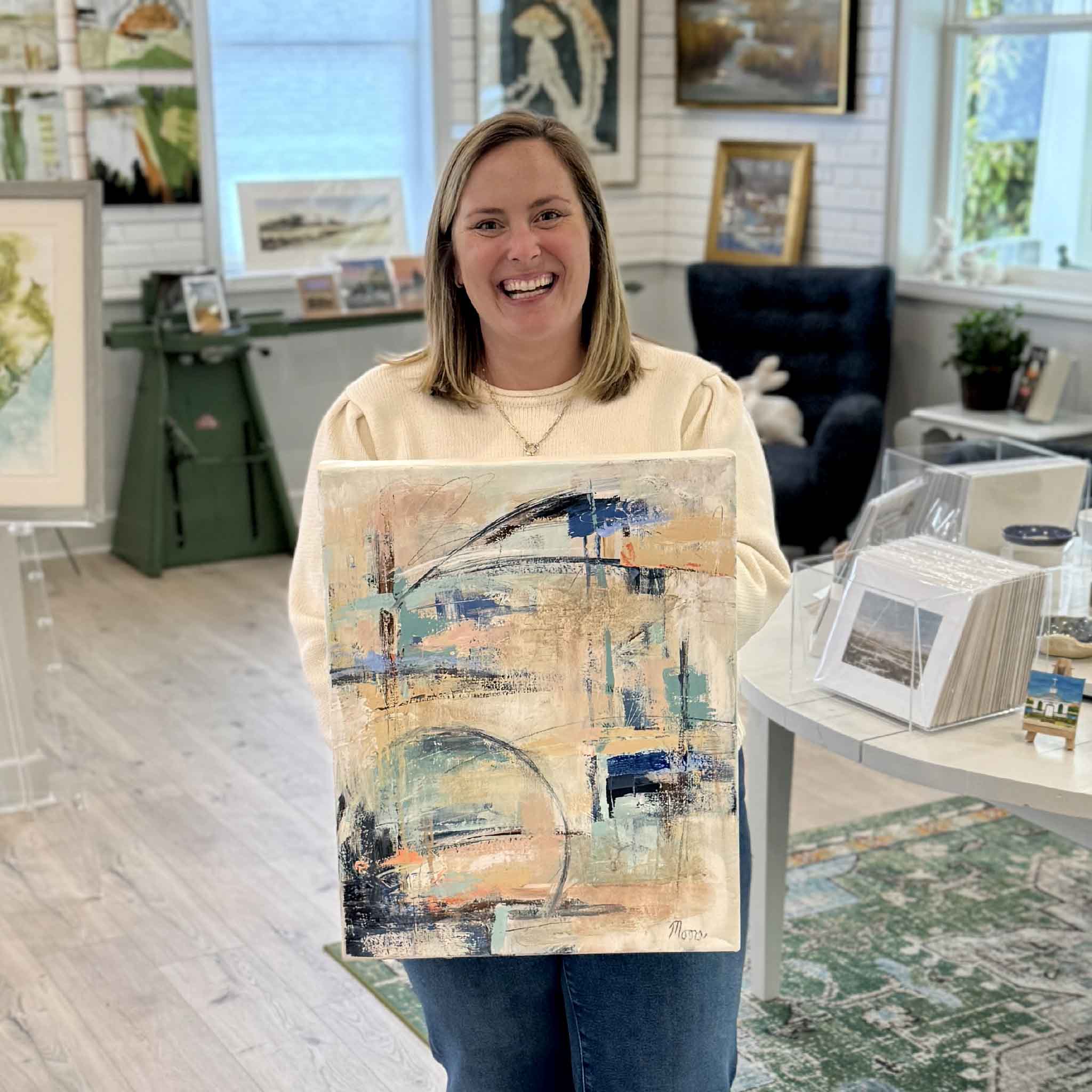 Bordy holding Caribbean Sunrise by local artist Susan Moore at Gray Man Gallery abstract acrylic painting on gallery-wrapped canvas with peach blue and neutral coastal tones
