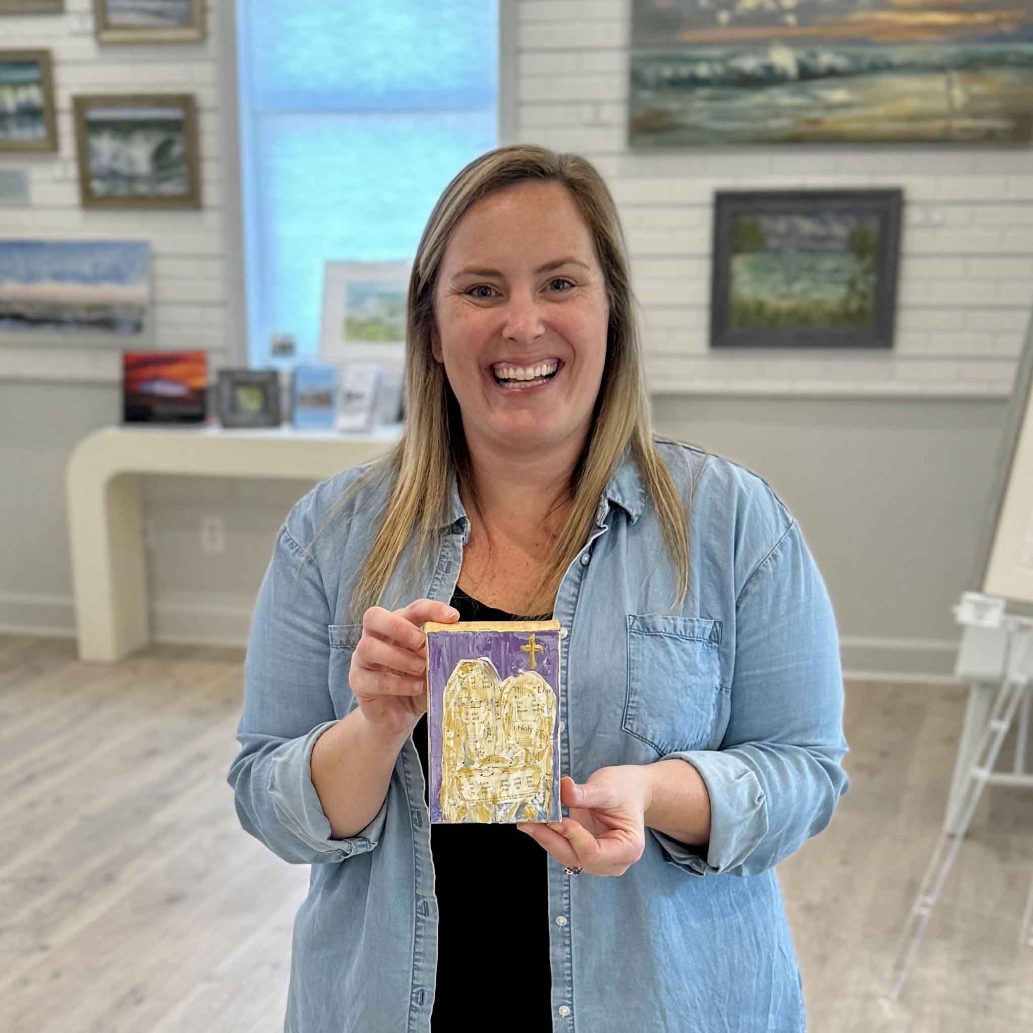 Bordy holding Golden Hymns, a mixed-media original artwork by Pawleys Island local artist Jeanne O’Neal created with vintage hymn sheet music and gold acrylic accents, available at Gray Man Gallery