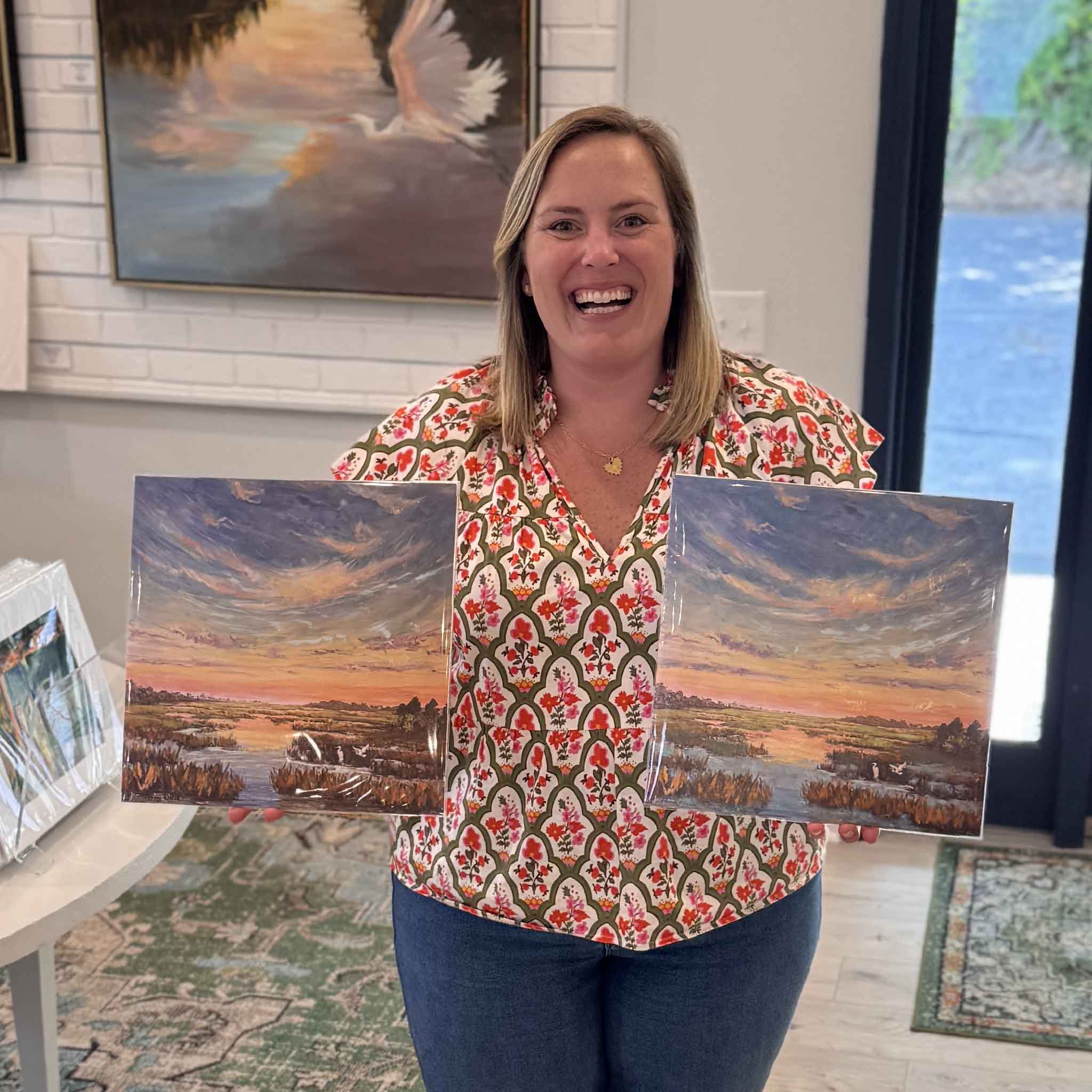Bordy holding Jeanne O’Neal Marsh at First Light enhanced giclée prints at Gray Man Gallery, showing hand-embellished Lowcountry marsh artwork inspired by Pawleys Island