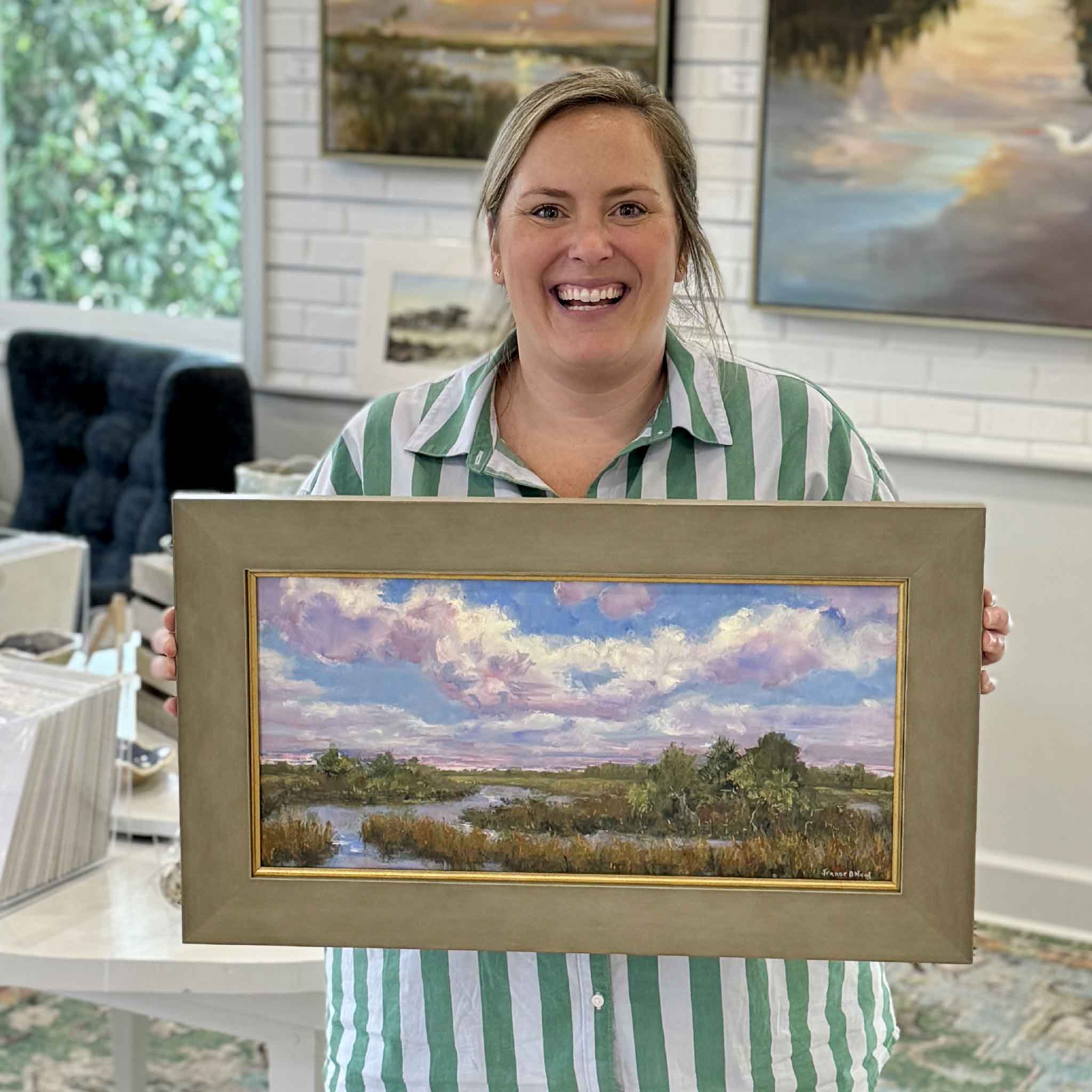 Bordy holds Marsh Reverie, an original framed oil painting by local Lowcountry artist Jeanne O’Neal at Gray Man Gallery in Pawleys Island, South Carolina. The painting features a peaceful coastal marsh scene with lavender clouds, tidal creeks, and warm marsh grasses painted in Jeanne’s expressive impressionistic style.