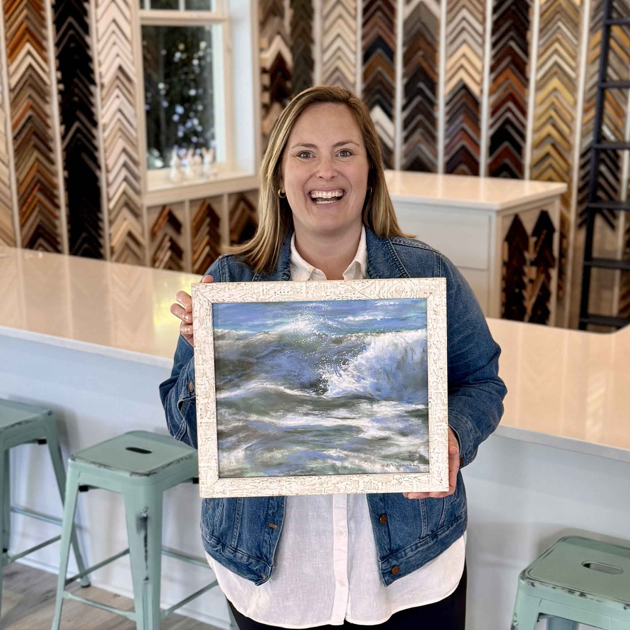 Bordy holding Power Point by Joanne Willoughby inside Gray Man Gallery in Pawleys Island, original pastel wave painting with movement, layered color, and textured coastal framing for scale and presentation