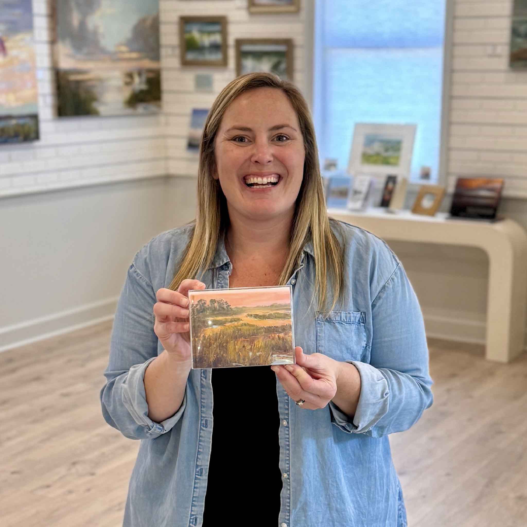 Gray Man Gallery team member holding Marsh Glow notecard set featuring Lowcountry marsh sunset artwork by local Pawleys Island artist Jeanne O’Neal