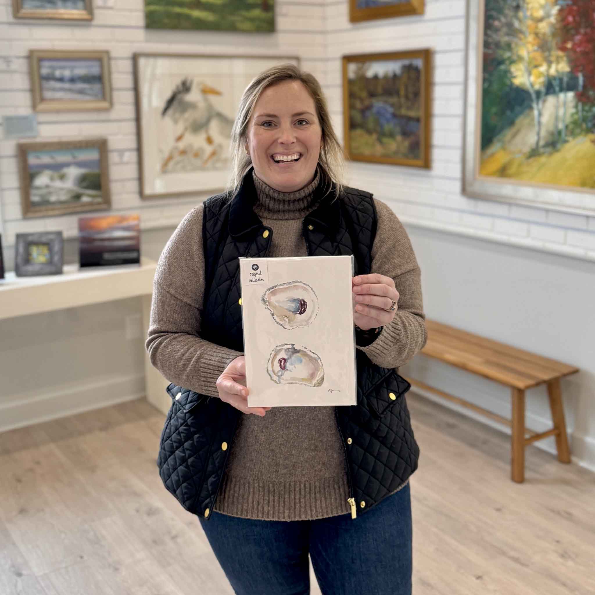 Bordy holding Surprise, an original oyster watercolor by local artist Allison Farr, part of the Lowcountry Jewels series at Gray Man Gallery in Pawleys Island