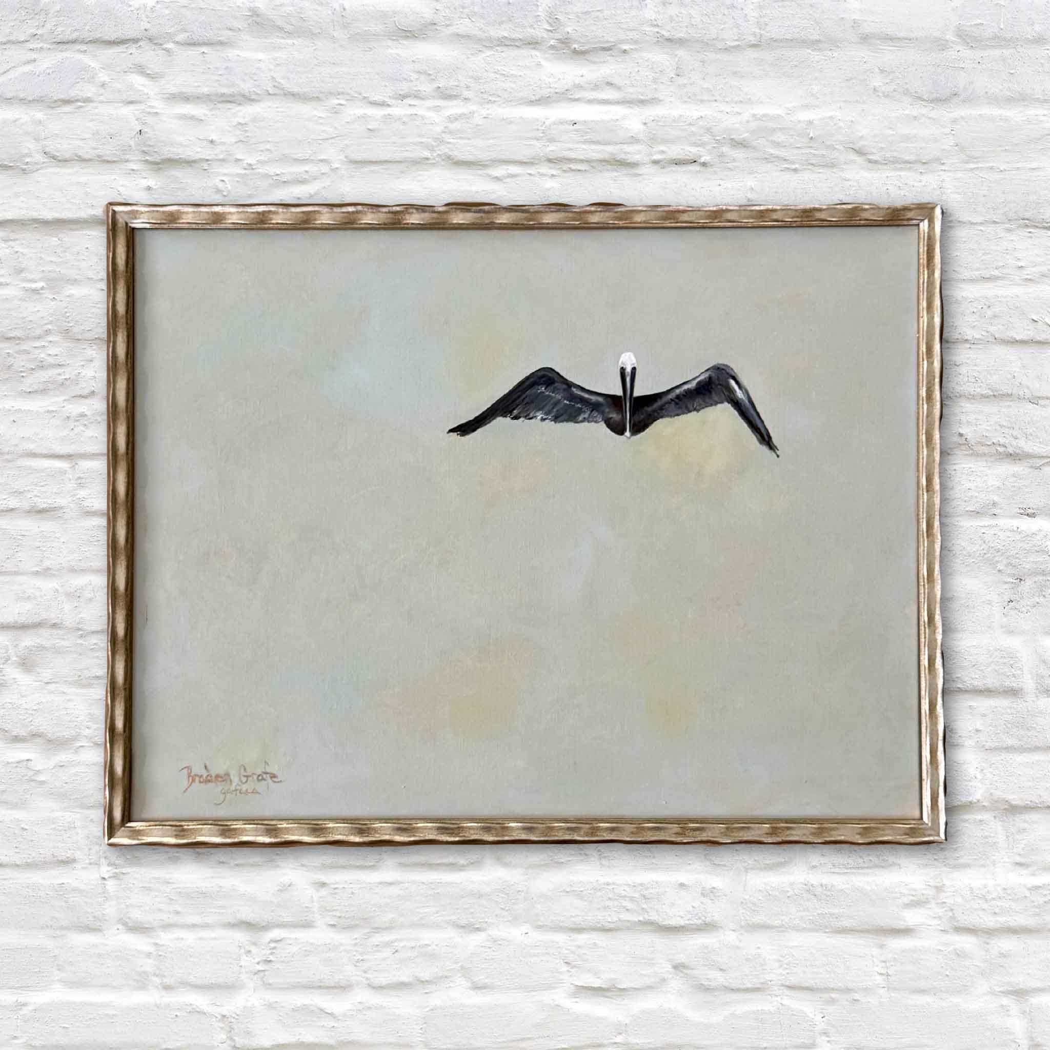 Braden Grafe original oil painting One featuring a single pelican in flight centered within a wide open neutral background with soft layered tones of sand, cream, and pale gray, framed coastal Lowcountry artwork at Gray Man Gallery in Pawleys Island highlighting minimal composition and quiet movement