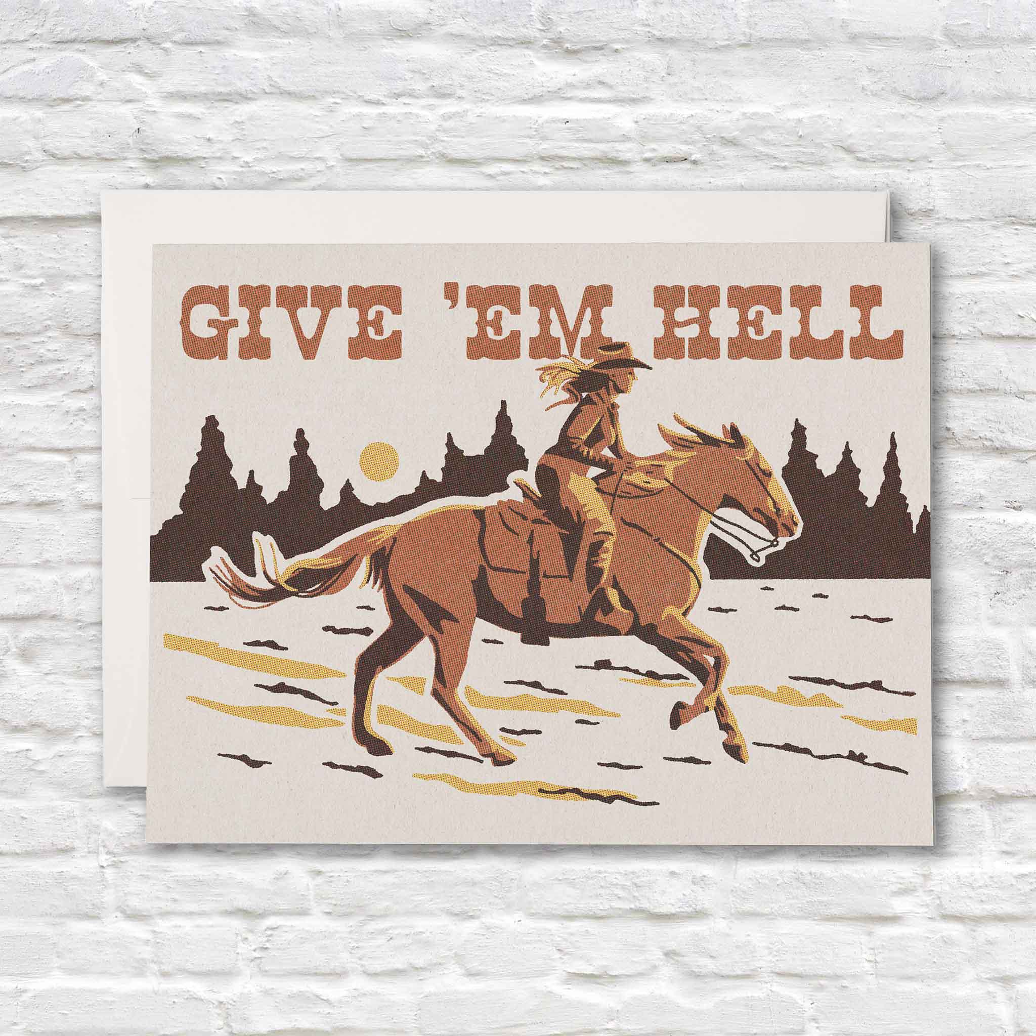 Give 'Em Hell greeting card by Caroline Clark for Red Cap Cards featuring a Western horseback rider galloping through an open landscape beneath bold vintage lettering. Available at Gray Man Gallery in Pawleys Island, South Carolina.
