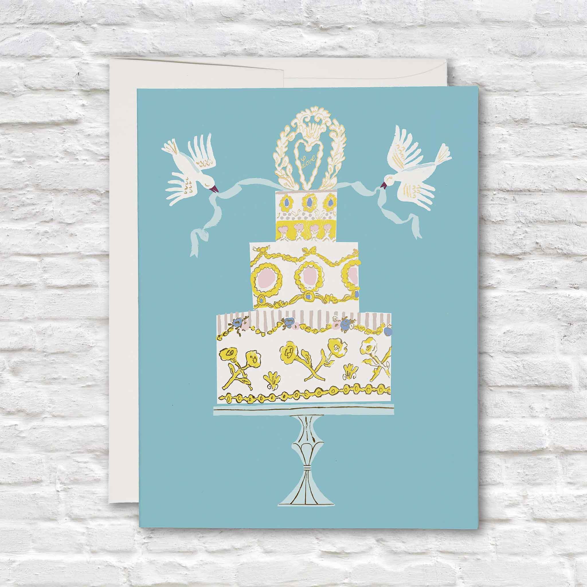 Love Cake wedding greeting card illustrated by Danielle Kroll for Red Cap Cards featuring a romantic wedding cake with gold foil accents, white doves, floral details, and a soft blue background. Shop this premium blank-inside wedding and anniversary greeting card at Gray Man Gallery in Pawleys Island, South Carolina.