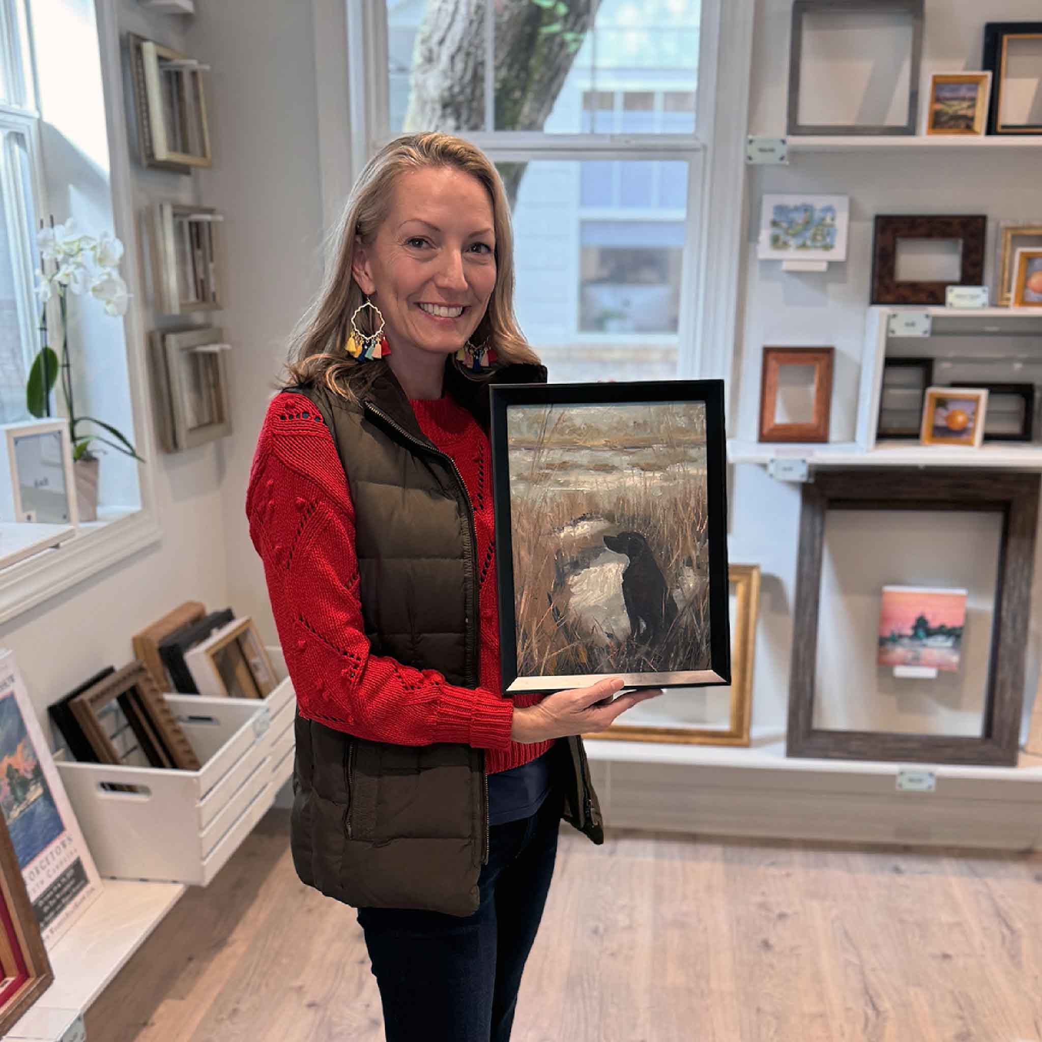 Local artist Jeanne O’Neal holding her Eyes in the Sky II original oil painting in the gallery, showing the artwork’s size and scale.