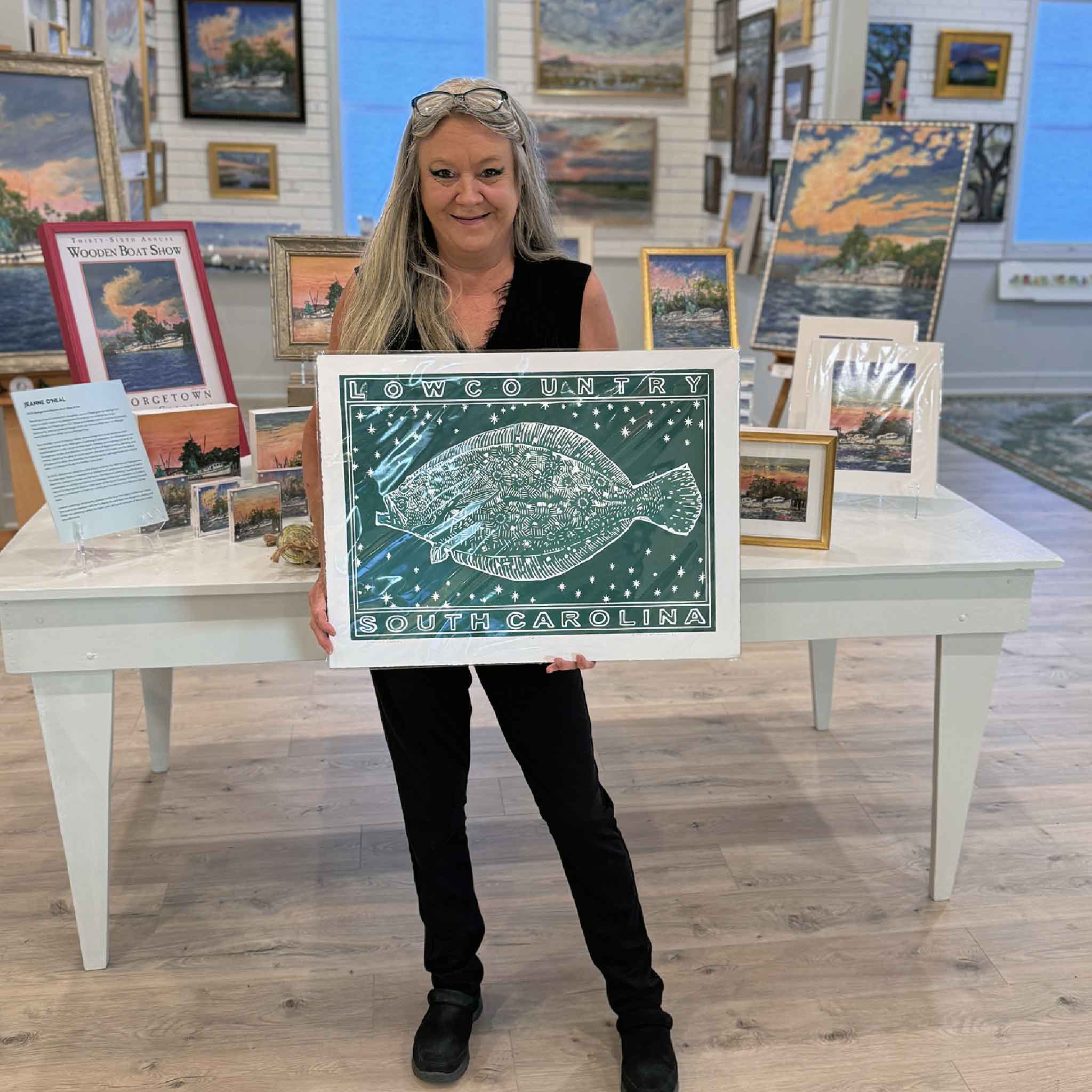 Charlotte holding the green Flounder linocut print by Aaron Baldwin at Gray Man Gallery.
