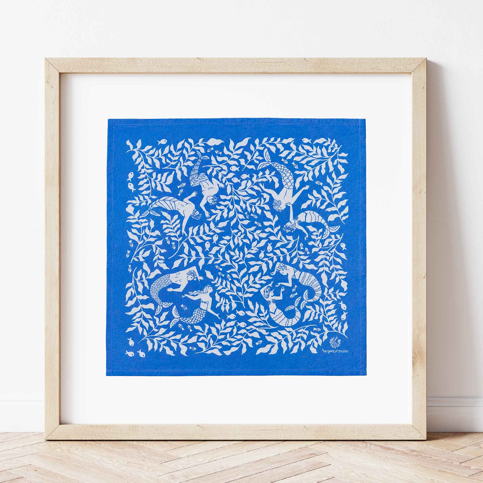 Cerulean Mermaid organic cotton bandana by Chrissie Van Hoever custom framed by Gray Man Gallery in Pawleys Island, South Carolina. Displayed as framed textile art with a wide white mat and natural wood frame, this whimsical mermaid design shows how a beautiful organic cotton bandana can become unique coastal wall art for a beach house, entryway, bedroom, or living room.