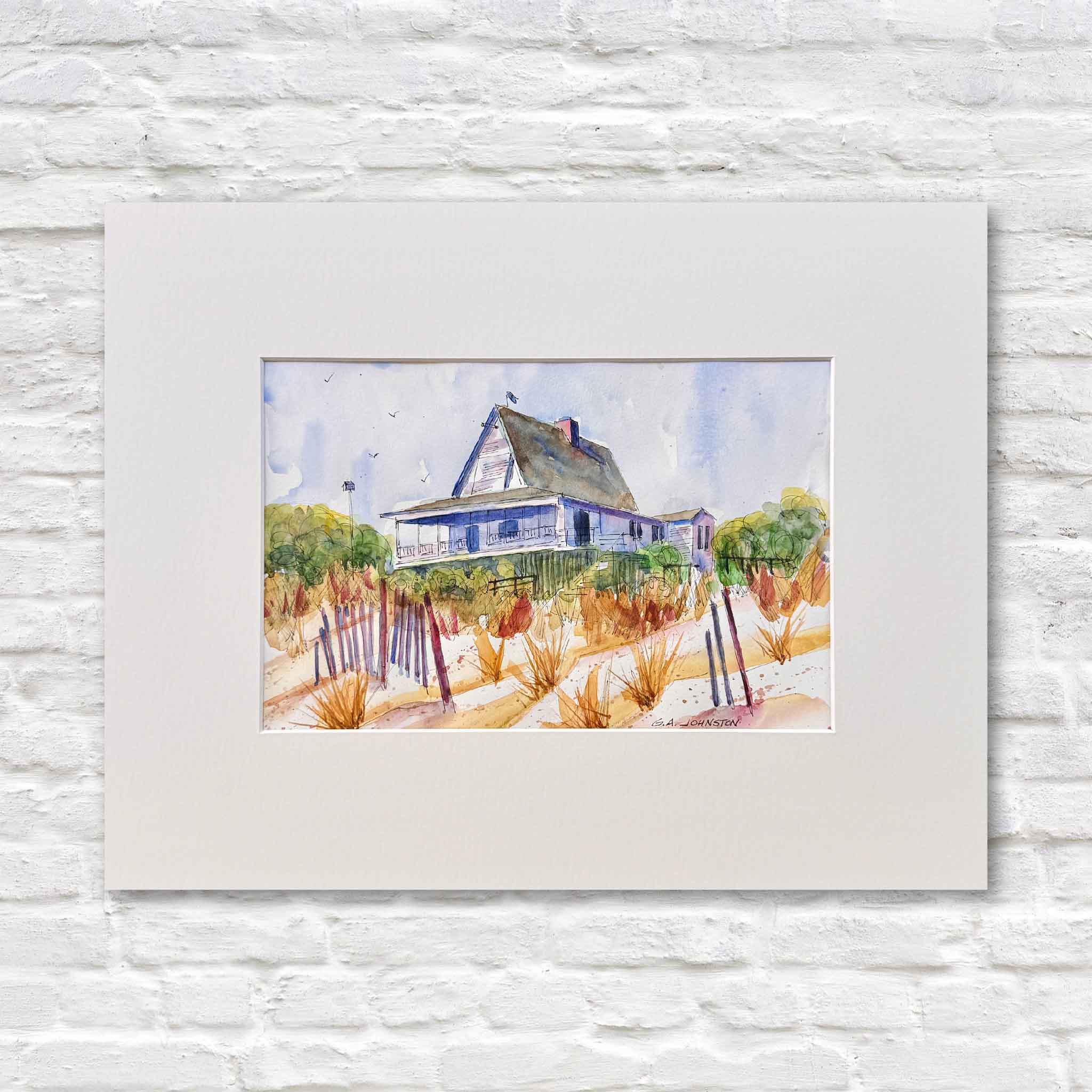 Original watercolor by Gary Johnston titled Pawleys Dune House featuring a classic Pawleys Island coastal home set behind sandy dunes, sea grass, and weathered fencing, softly painted in loose expressive washes, matted to fit a standard 14x18 frame like those offered at Gray Man Gallery, photographed against a white gallery wall to highlight the Lowcountry landscape and natural color palette