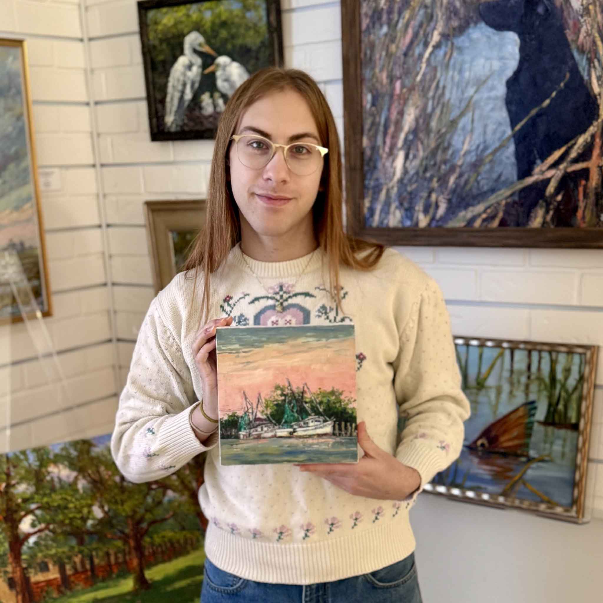 A Gray Man Gallery team member holding the Coral Sky Harbor wrapped canvas giclée by Jeanne O’Neal to show scale and presentation in the gallery.