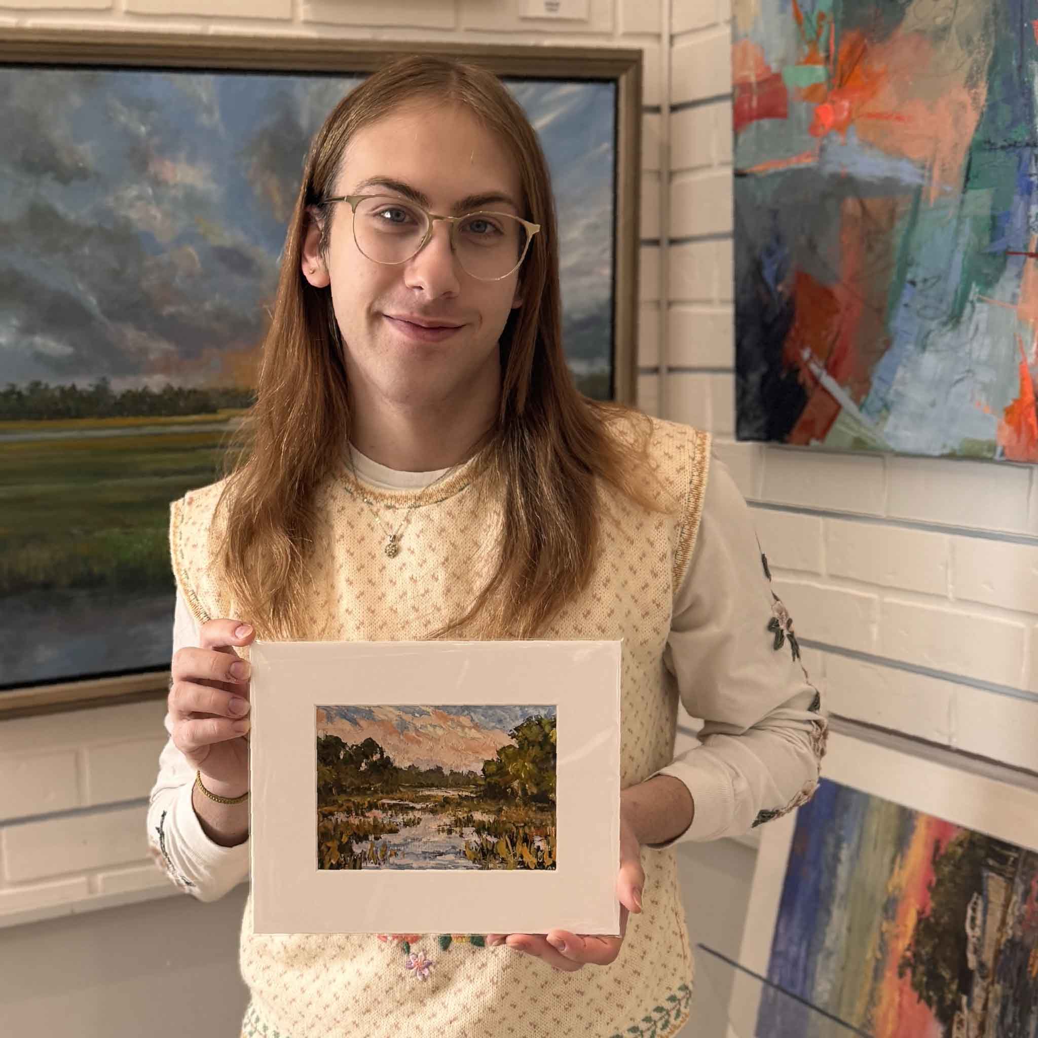 A Gray Man Gallery team member holding the Wish You Were Here giclée print by Jeanne O’Neal to show scale and presentation.
