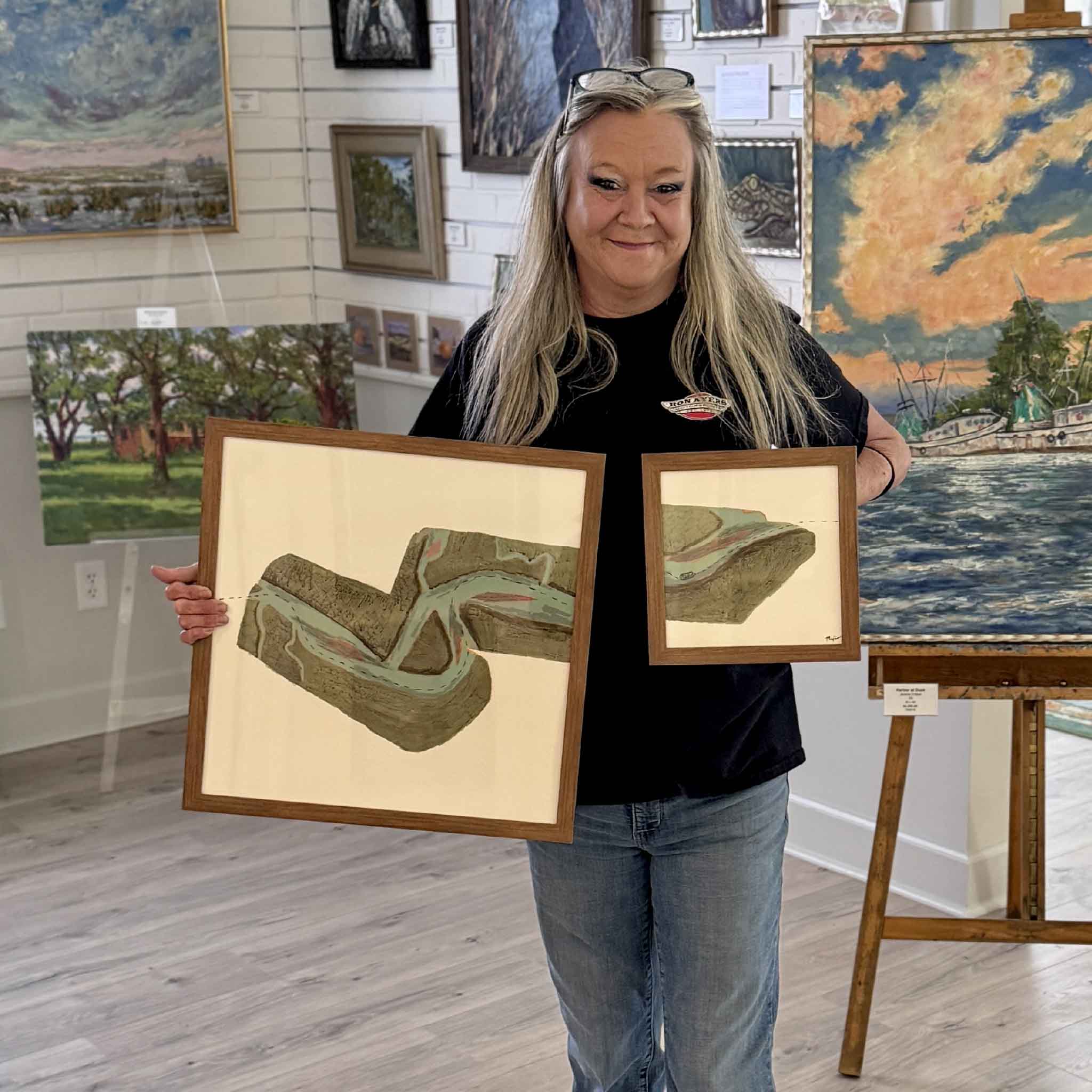Charlotte holding both pieces from artist Maggie Pelton's Aids to Navigation installation inside Gray Man Gallery, shown together for scale and context.