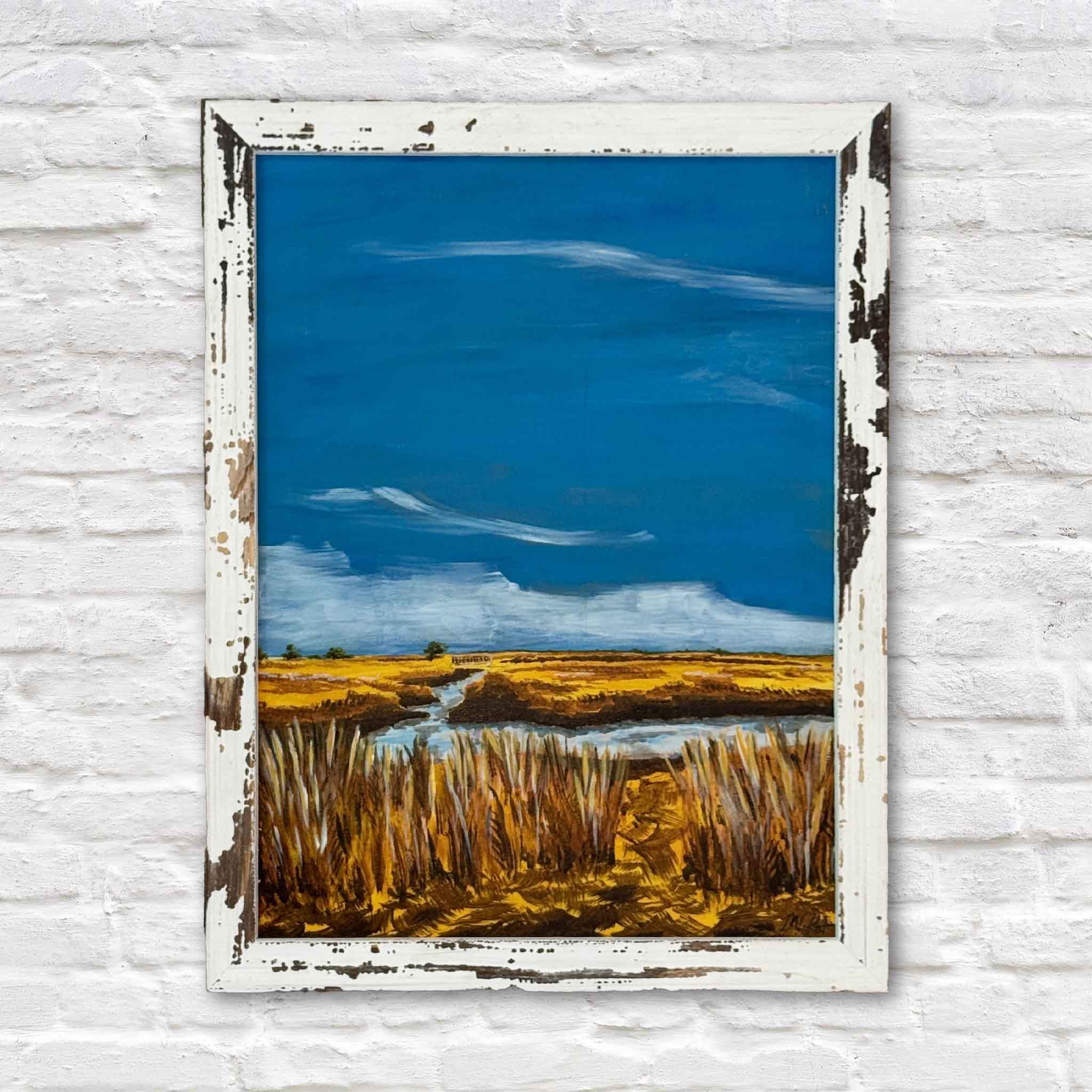 Autumn Sun at Clambank by Maggie Pelton is a framed original acrylic painting inspired by North Inlet, featuring golden autumn marsh grass, winding tidal creeks, and brilliant blue Lowcountry skies. Professionally framed in a distressed white wood frame and available at Gray Man Gallery in Pawleys Island, South Carolina.