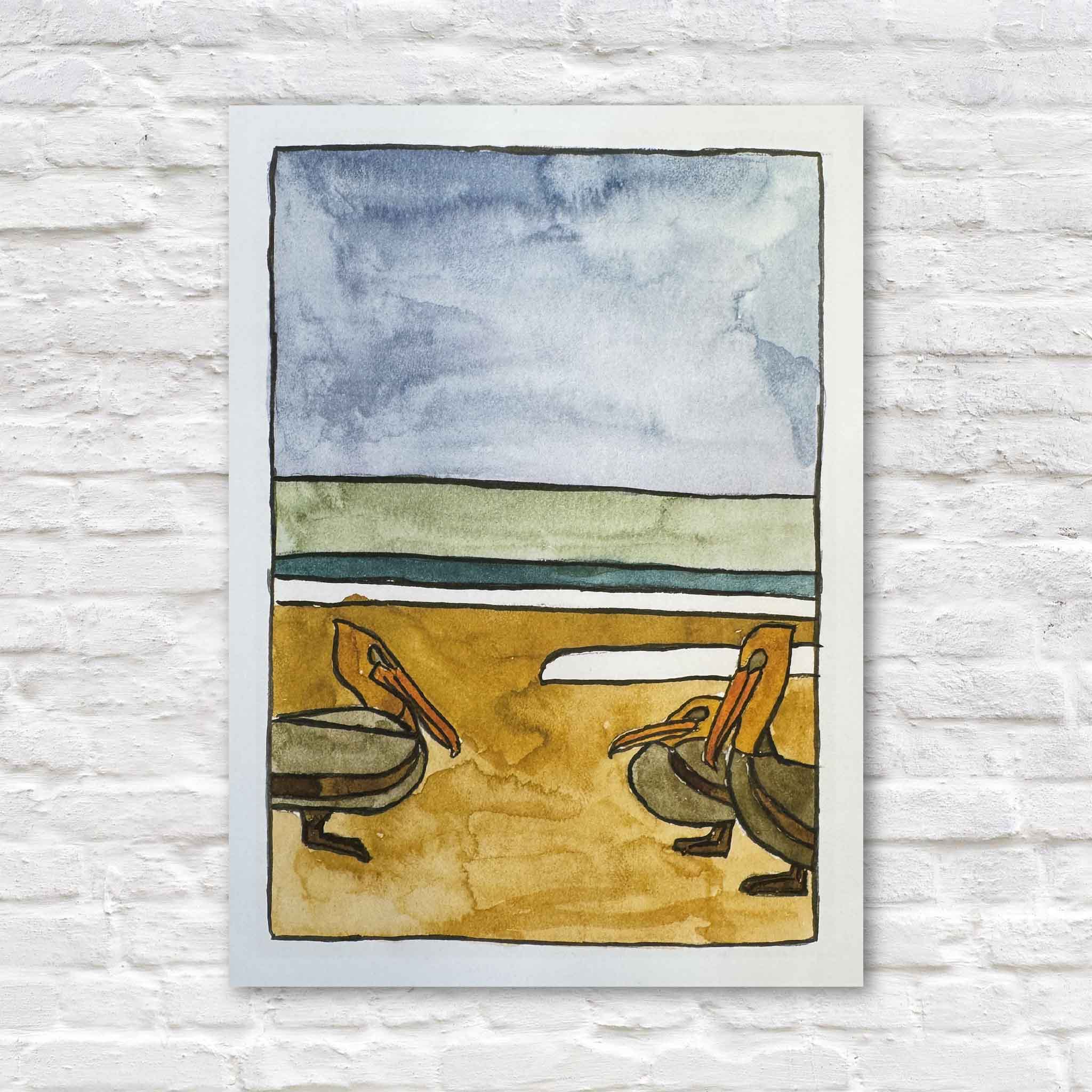 Pelican, a 5 x 7 coastal giclée print by Maggie Pelton, depicts two brown pelicans standing along a sandy shoreline with calm water and expansive Lowcountry skies. Available at Gray Man Gallery in Pawleys Island, South Carolina.