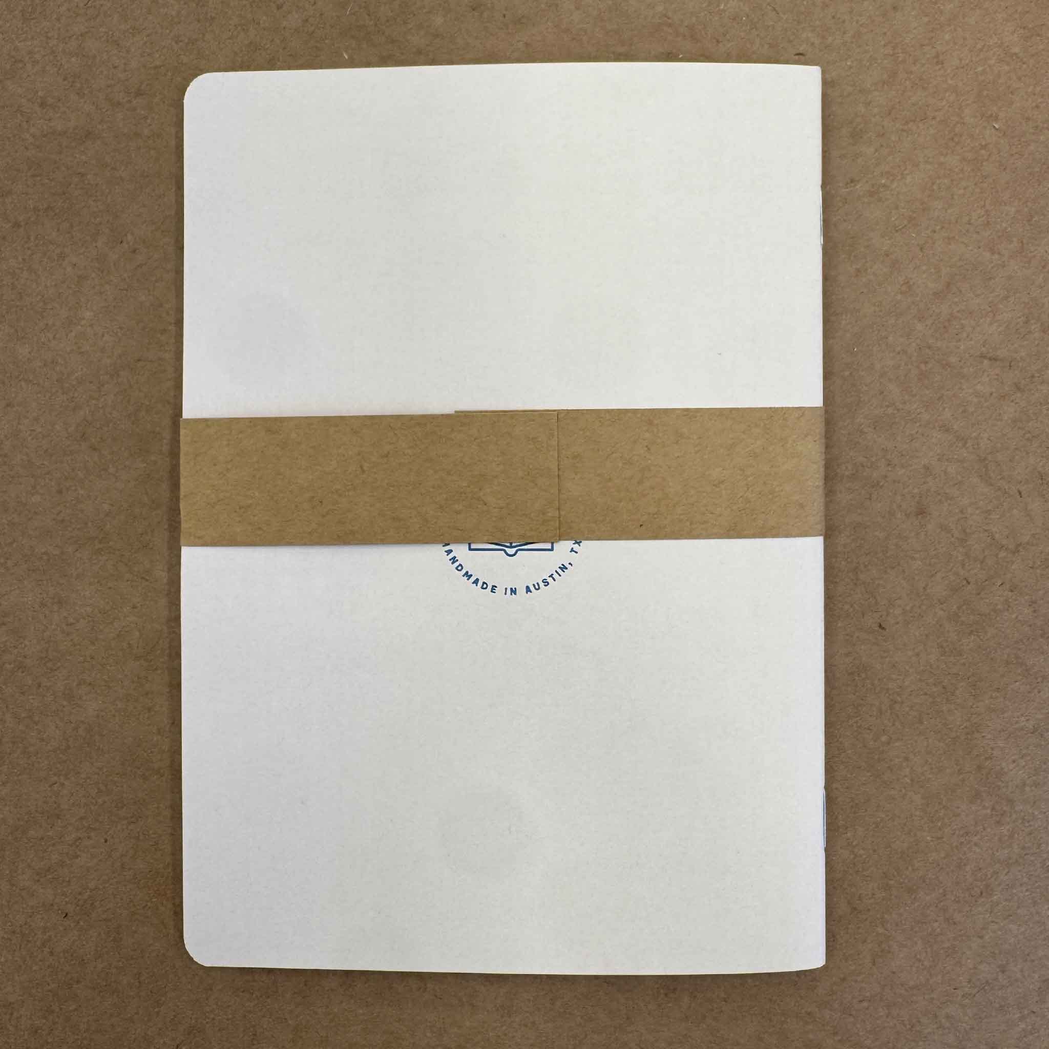 Back cover of the Yellow Floral Notebook by Justin Ryan Books showing the simple kraft belly band and handmade construction. This 5x7 notebook includes 48 blank pages and is available at Gray Man Gallery in Pawleys Island, South Carolina.
