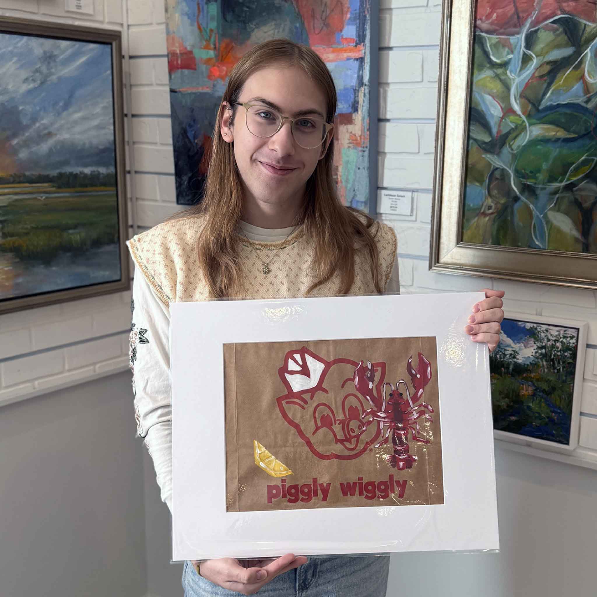 Team member holding the Piggly Wiggly Lobster and Lemon artwork to show scale and presentation in the gallery.