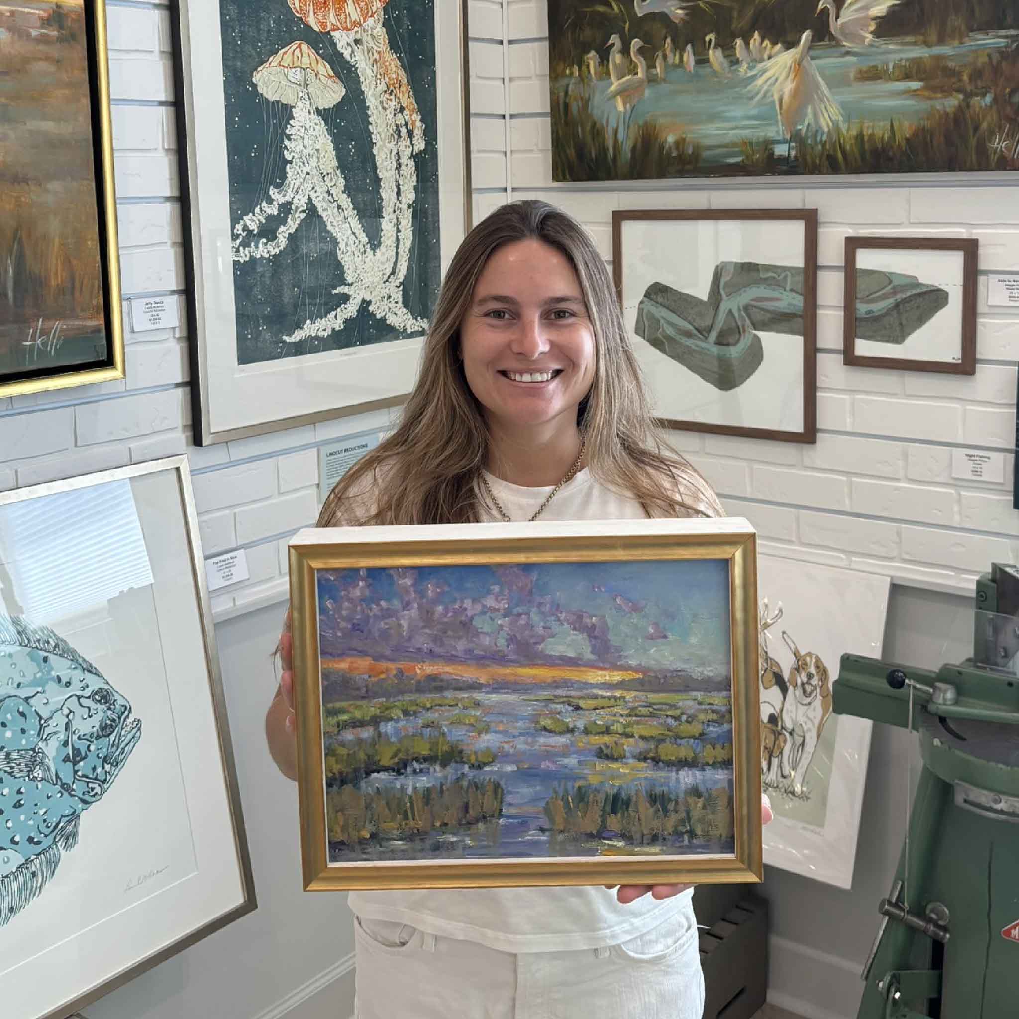 Daybreak by Jeanne O’Neal, an original Lowcountry marsh oil painting, shown held inside Gray Man Gallery in Pawleys Island, South Carolina, with its gold frame and vibrant sunrise landscape on display.