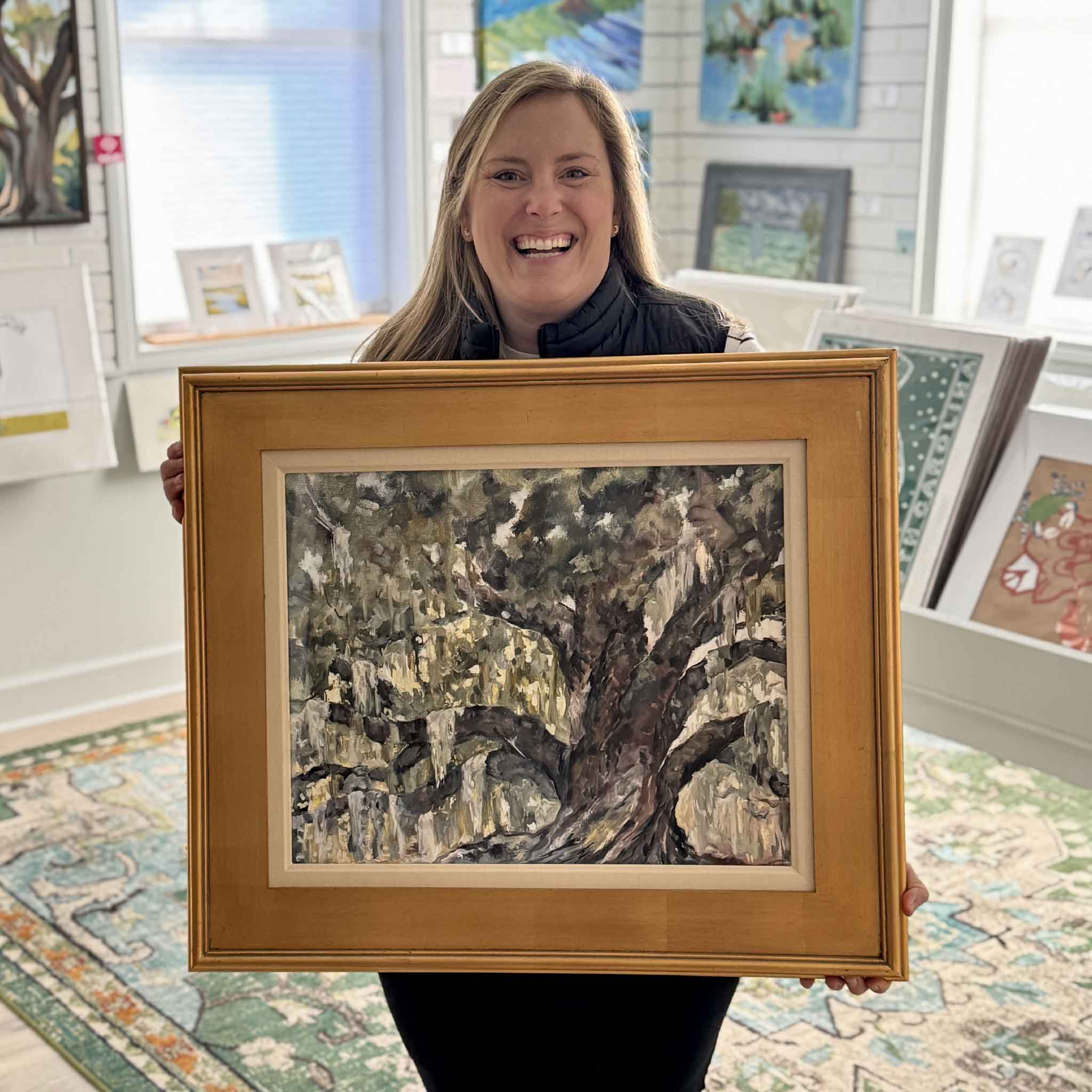 Large framed Deep Roots fine art print by Jeanne O’Neal, shown in a gold frame and held for scale inside Gray Man Gallery, showcasing a dramatic Lowcountry live oak landscape.