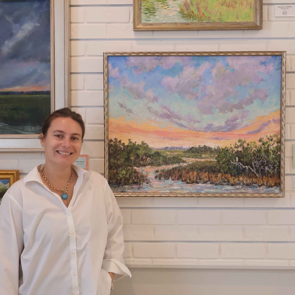 Jeanne O’Neal’s framed original oil painting Joyful Solitude shown inside Gray Man Gallery in Pawleys Island, South Carolina, featuring a colorful Lowcountry marsh landscape with tidal water, coastal grasses and a luminous pastel sunset sky